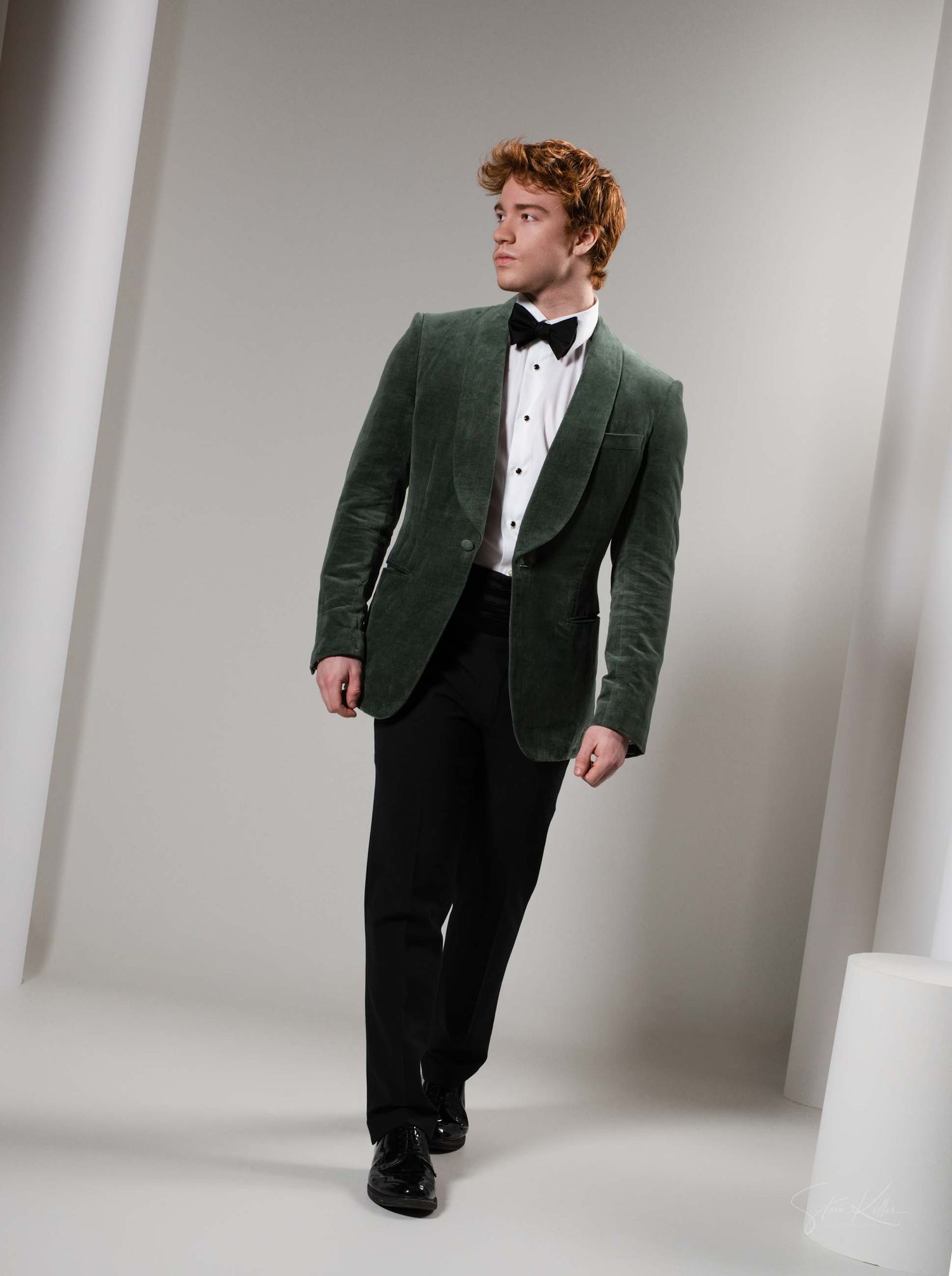 Person in dark green velvet suit and white shirt poses against white backdrop in four different angles.