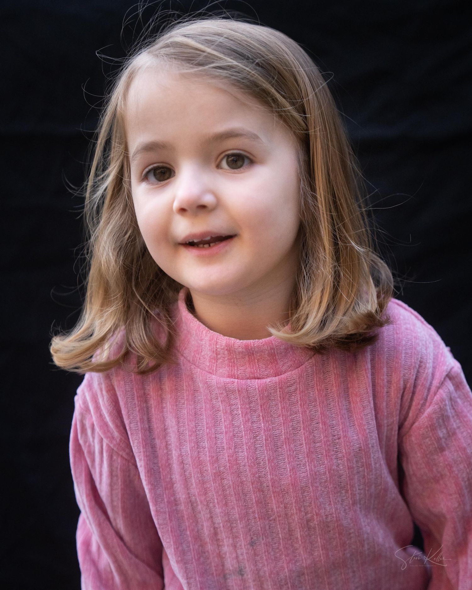 A young child wearing a pink sweater smiles and makes playful expressions in a series of candid portrait shots.