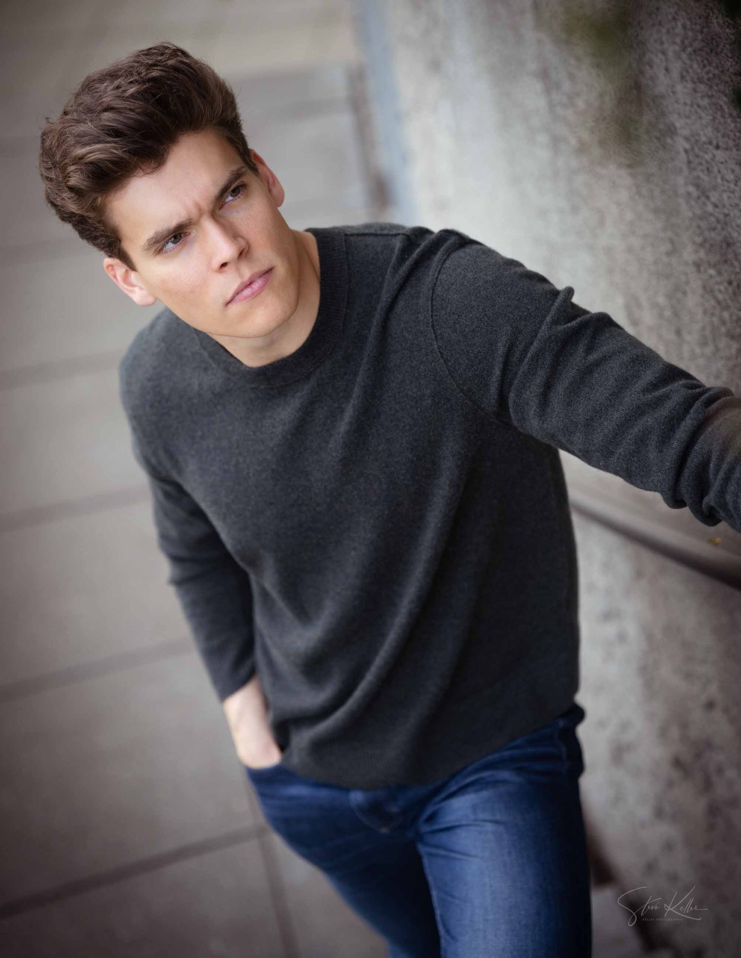 Portrait photo series of someone in a dark sweater and jeans against a textured wall in moody lighting.