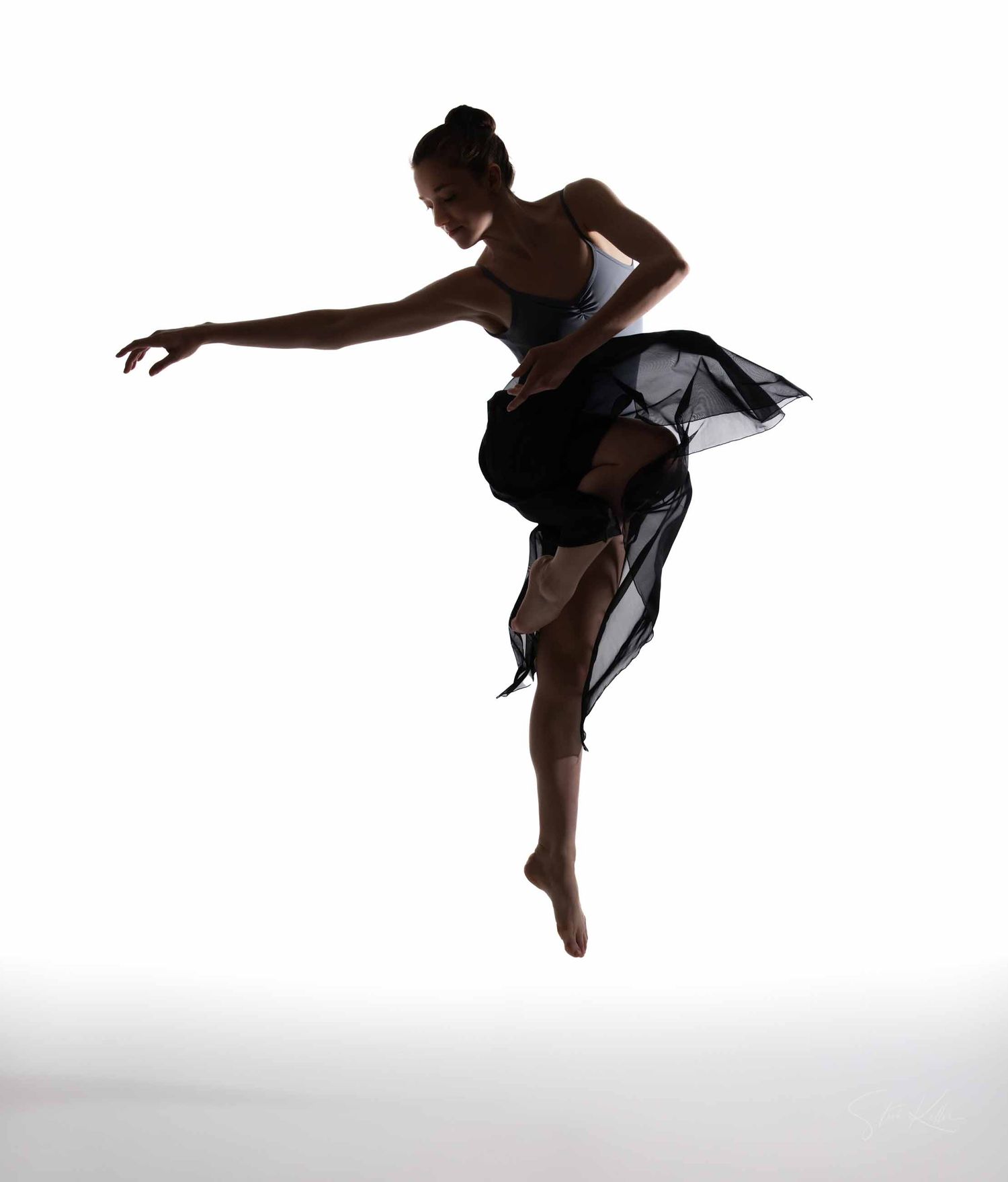 Silhouetted dancer in black leotard performs graceful leaps and poses against white background in artistic sequence.