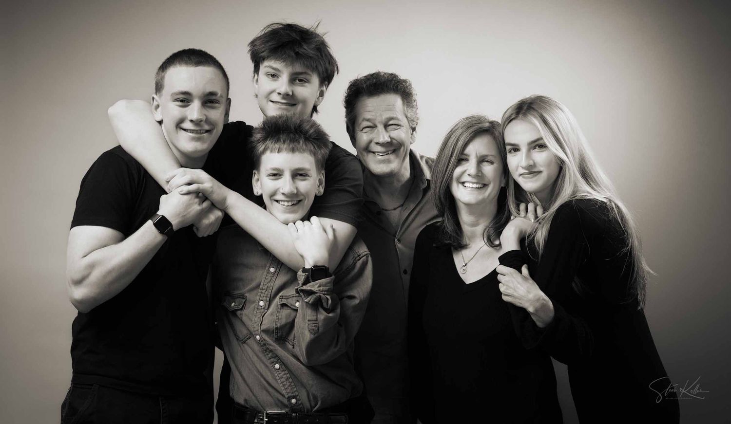 Black and white studio portrait of a family group of five people smiling and posing together.