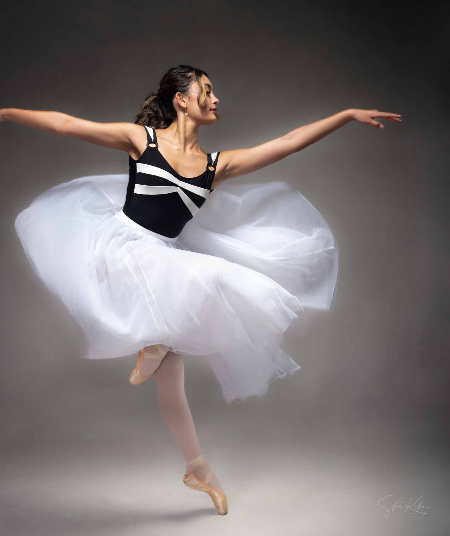 Graceful ballet dancer in white tutu performs elegant leaps and poses against dark dramatic backdrop.