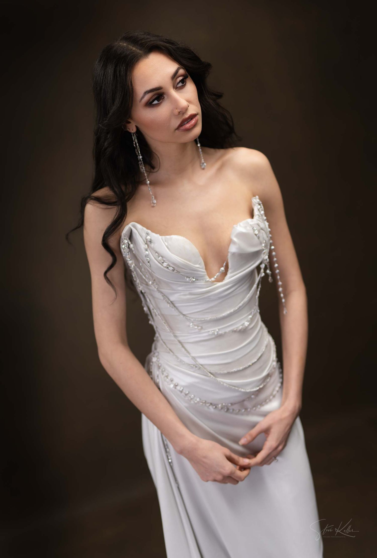 Romantic bridal portrait featuring draped white satin gown with sweetheart neckline in studio setting.