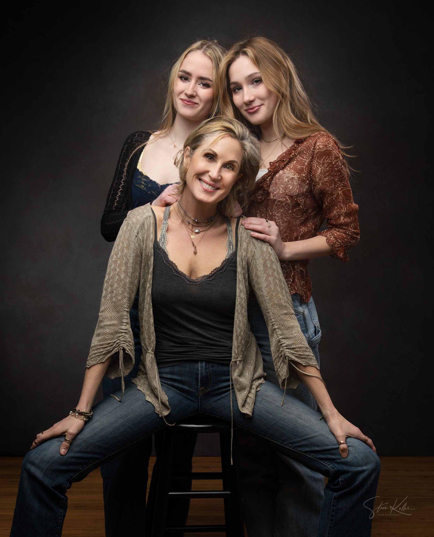 Two people in casual attire pose playfully together against a dark background in a series of studio portraits.