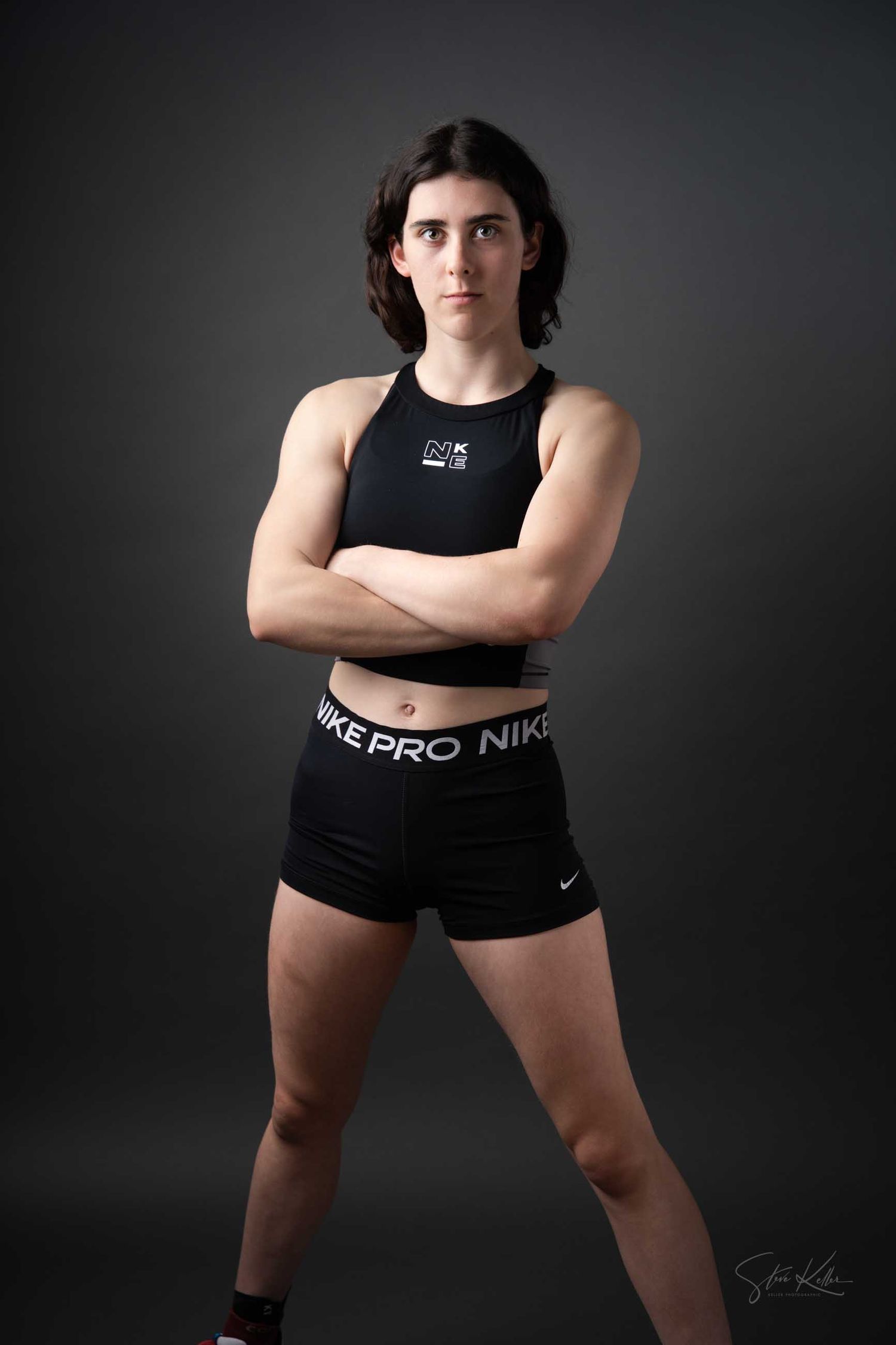 Athletic figure in black Nike sportswear demonstrates dynamic poses in dark studio setting.
