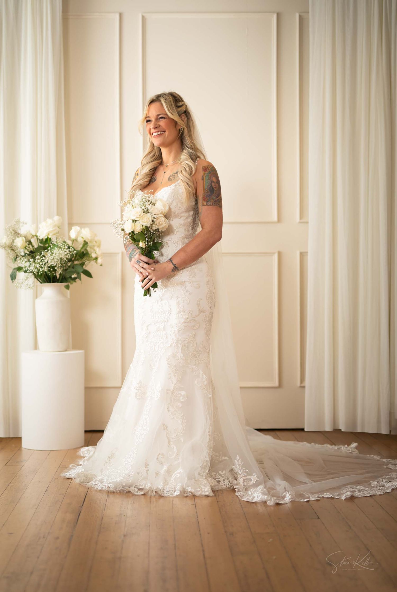 A stunning bridal portrait series showing a lace wedding gown with cathedral train against white paneled walls and wood floors.
