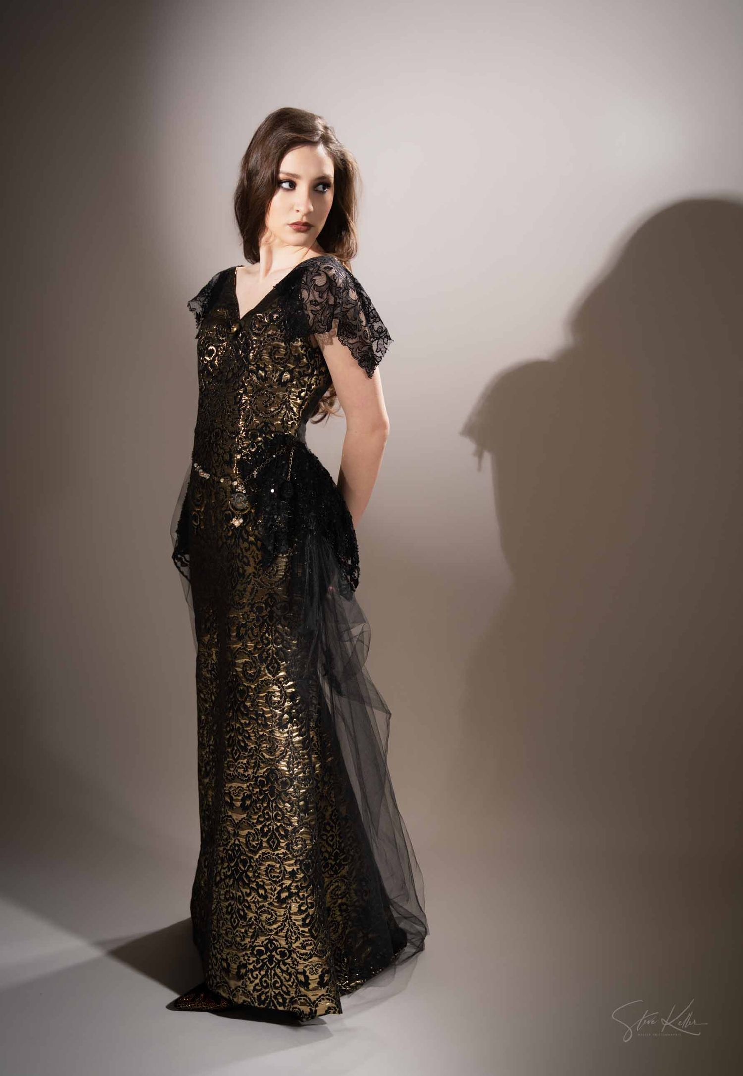 A model in a black and gold sequined dress poses dramatically against a light backdrop in a fashion photoshoot series.