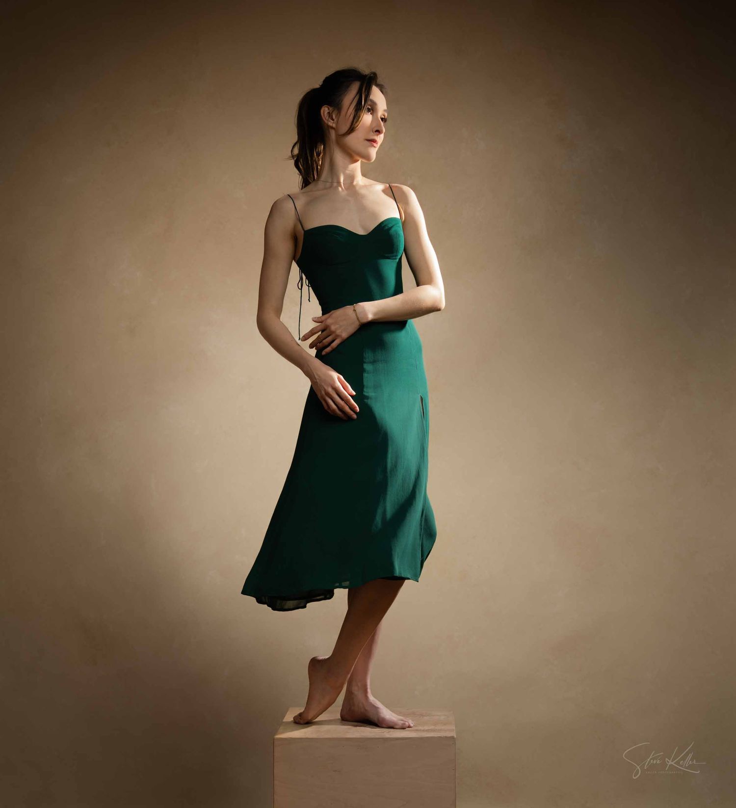 Figure in an emerald green dress poses gracefully in a series of artistic dance movements against a neutral backdrop.
