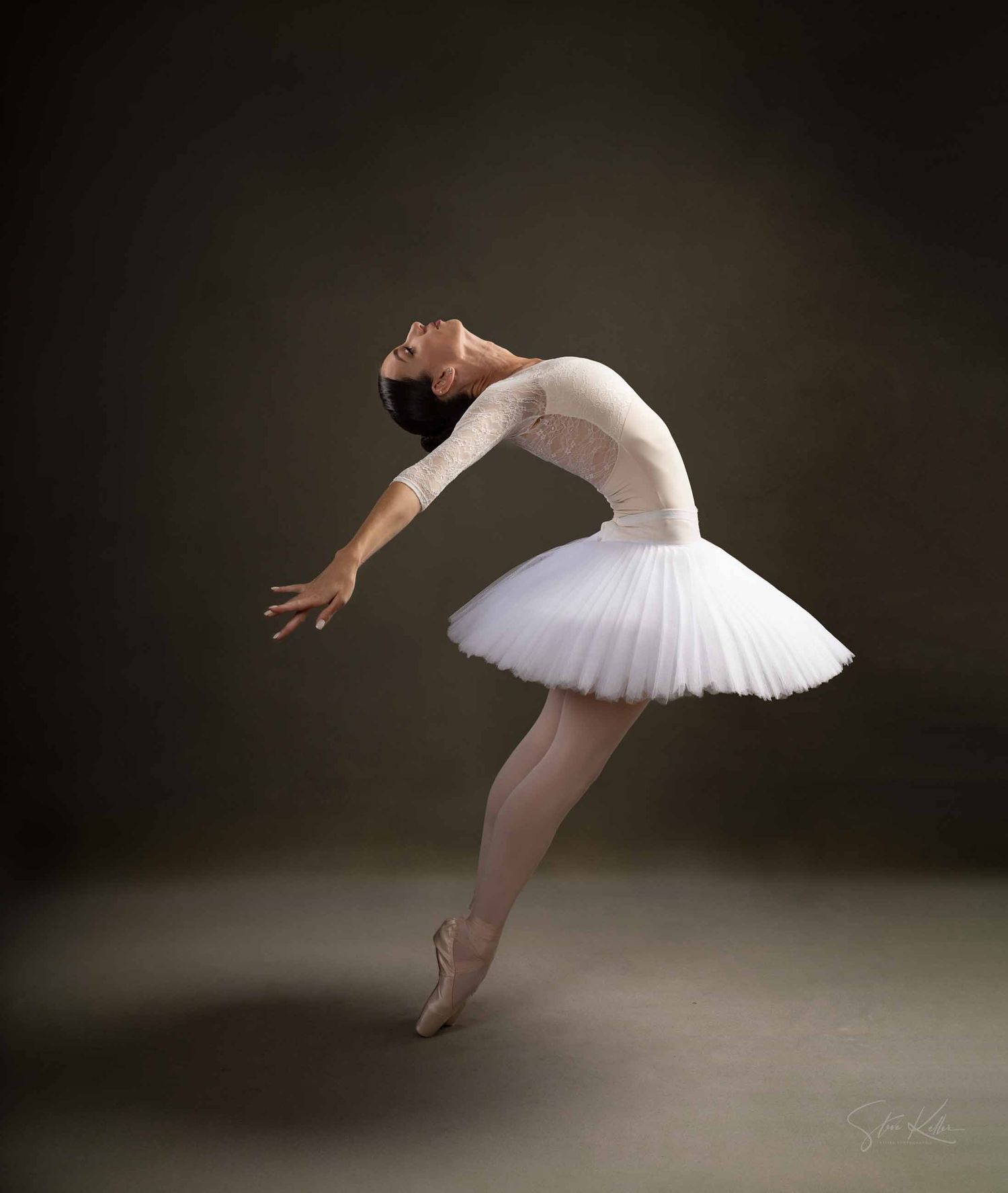 A ballet dancer in a white tutu performs a graceful sequence of leaping movements against a dark background.