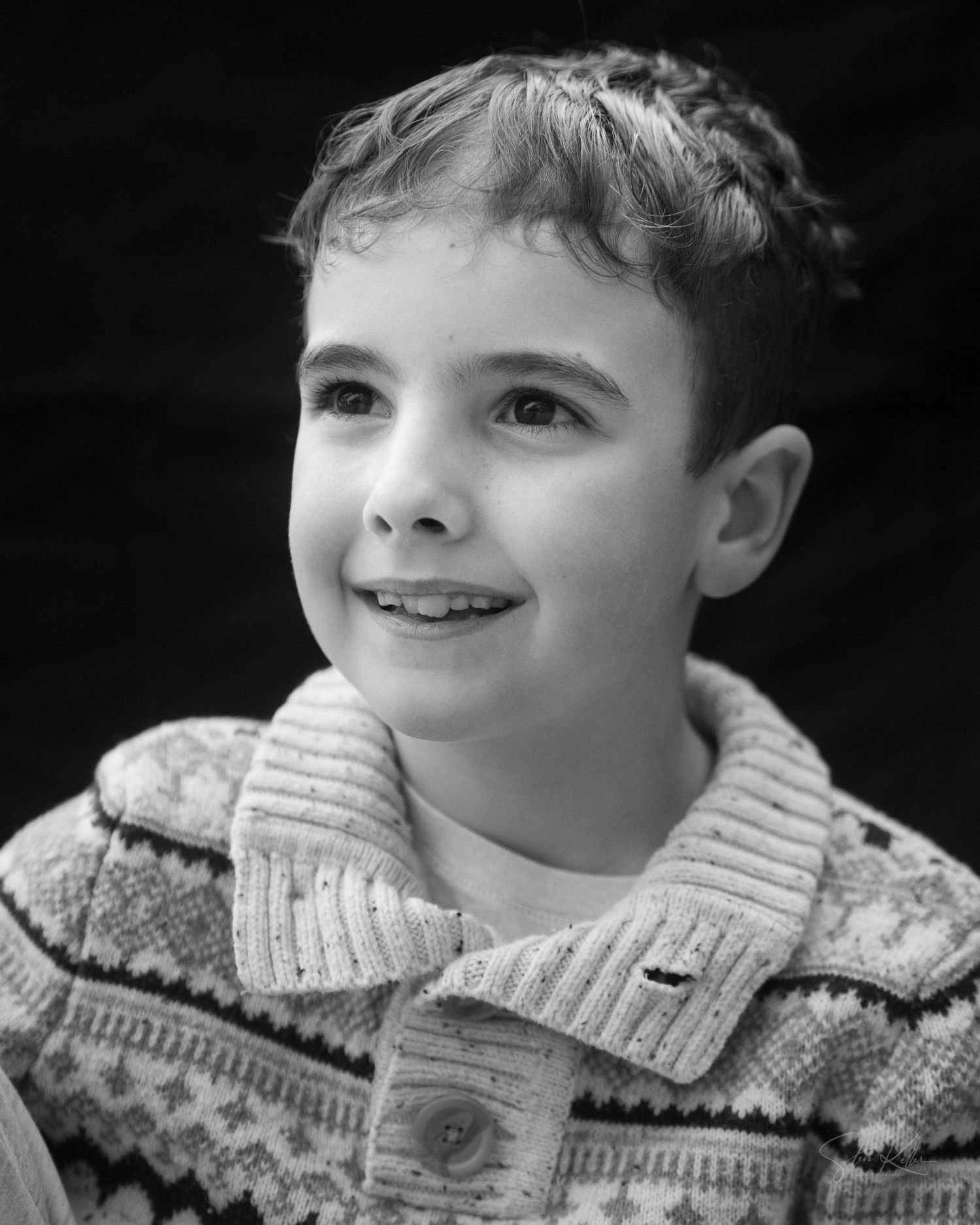 A series of black and white portraits showing a young child in a knit sweater with changing expressions.