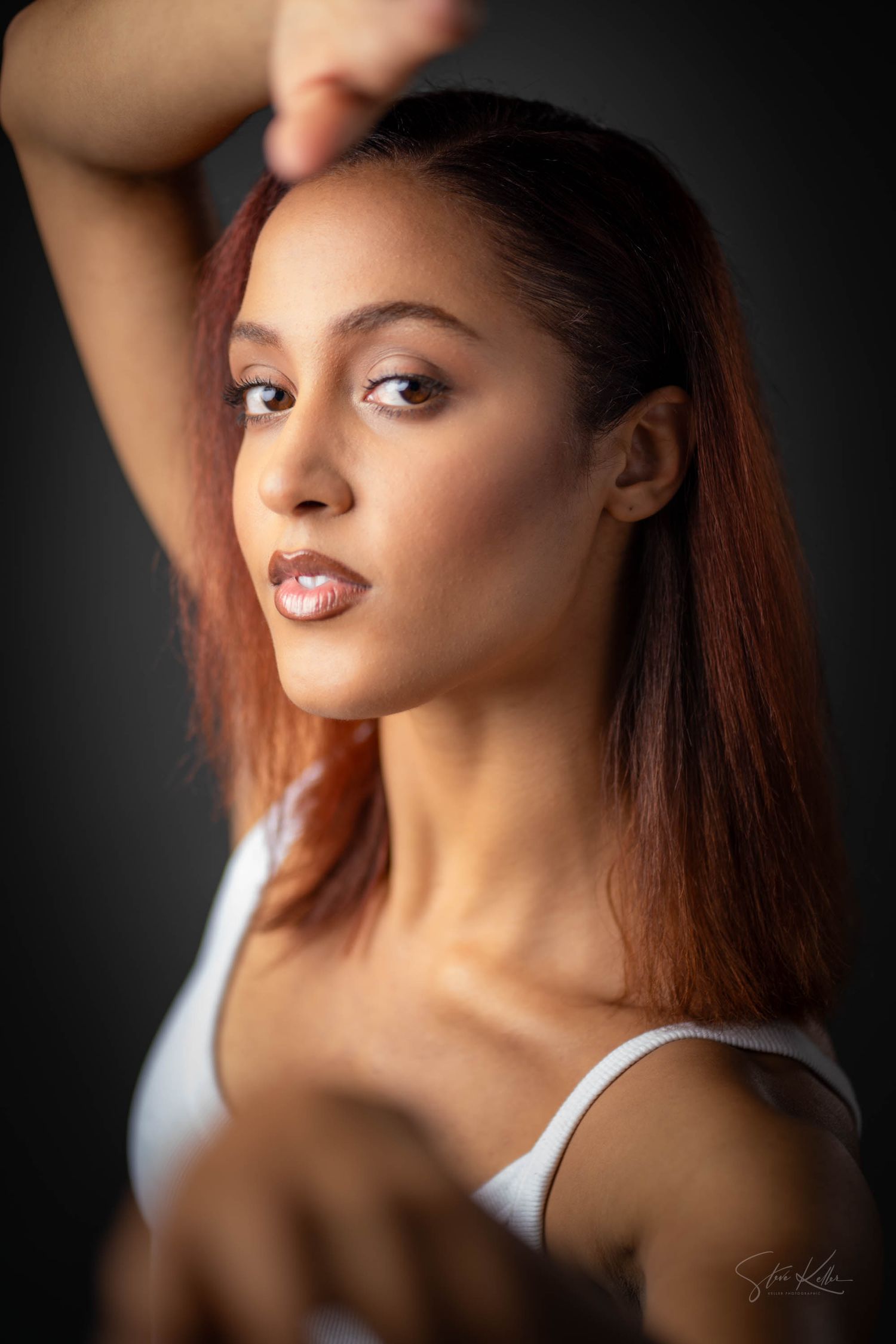 Fashion portrait with dramatic lighting showcasing rich auburn hair and professional makeup in studio setting.
