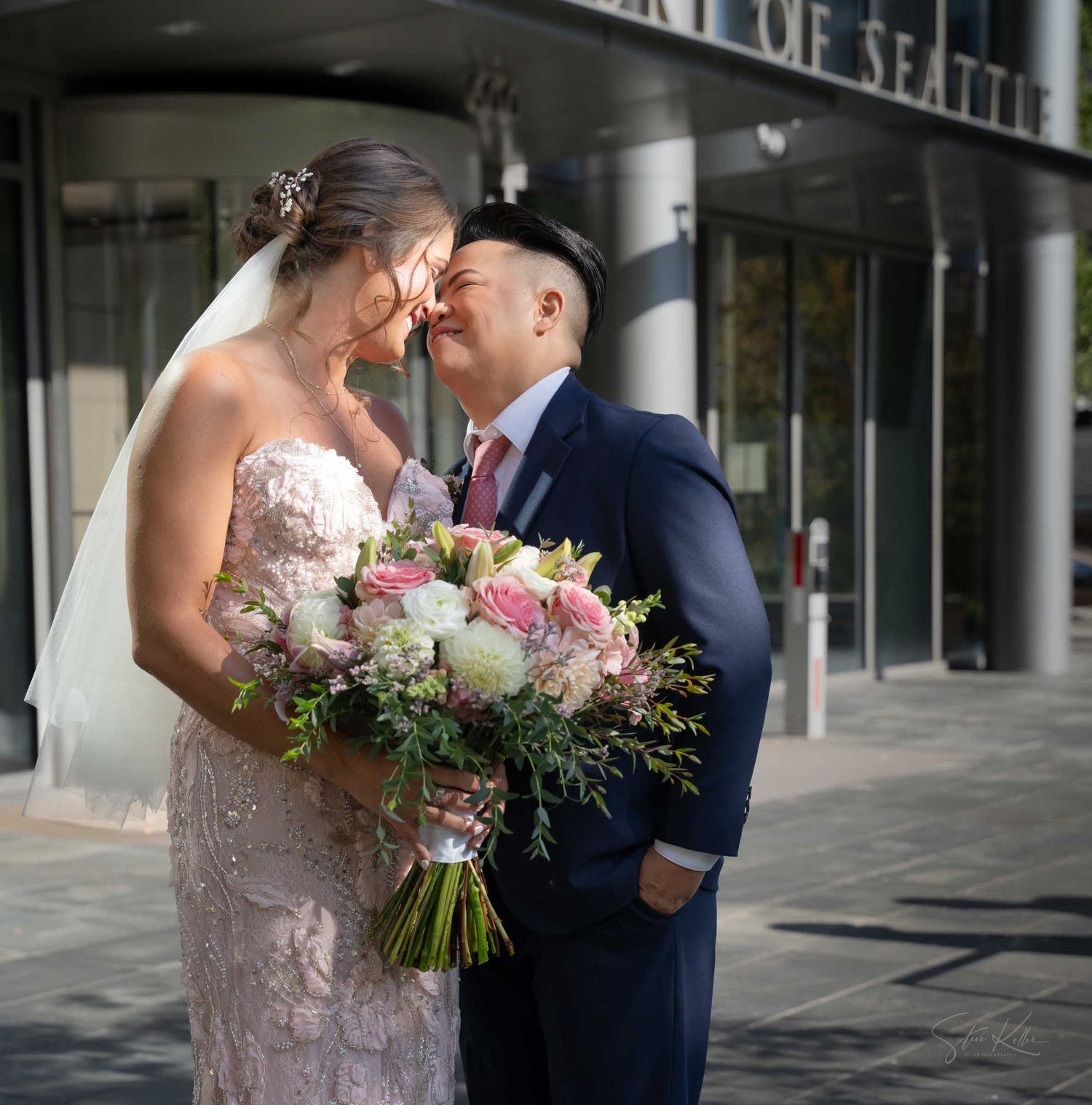 Bride and groom share a romantic moment outside Seattle City Hall, bride holding pink and white bouquet.