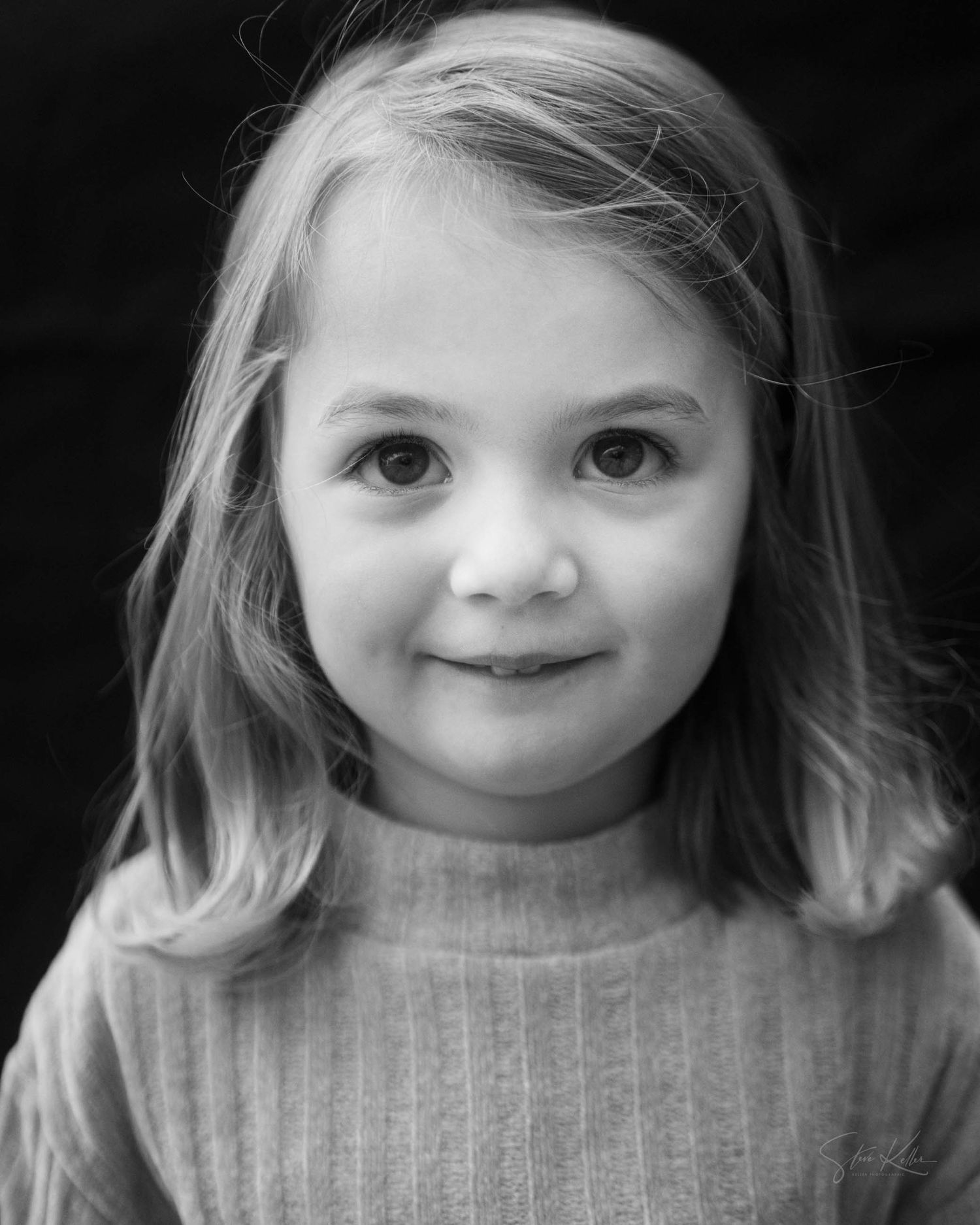 A sequence of black and white portraits showing a young child with expressive smiles and various playful expressions.