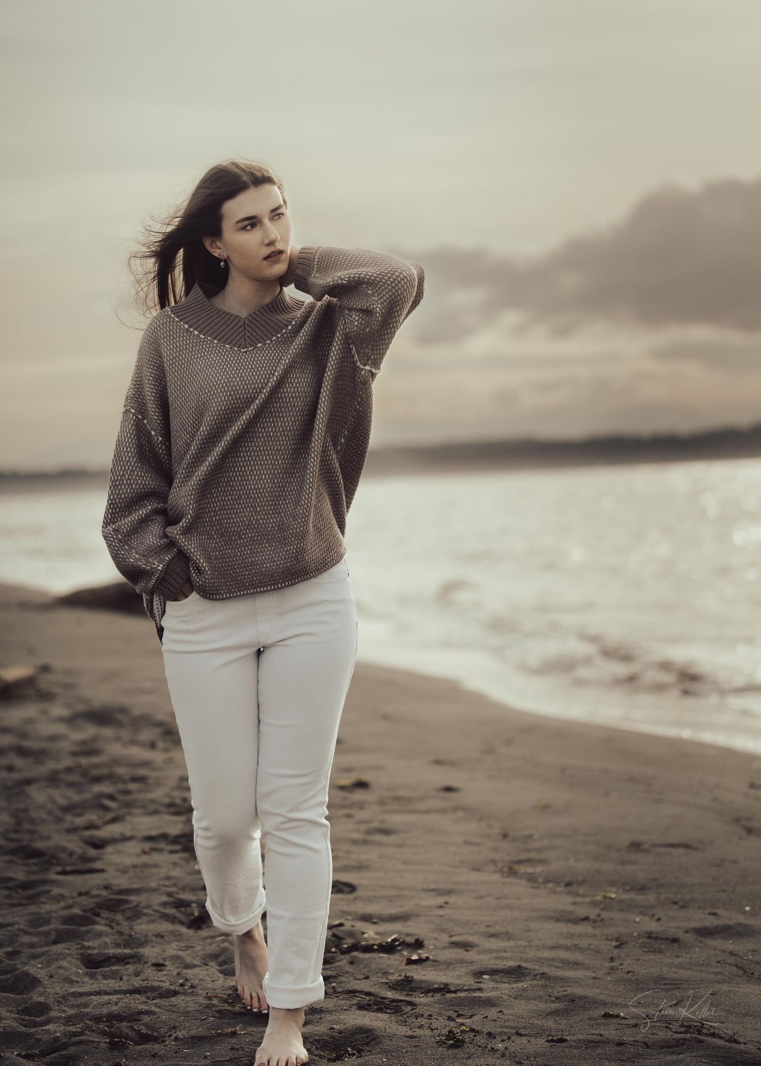 Atmospheric beachwear photo featuring oversized brown sweater and white pants along foggy shoreline.