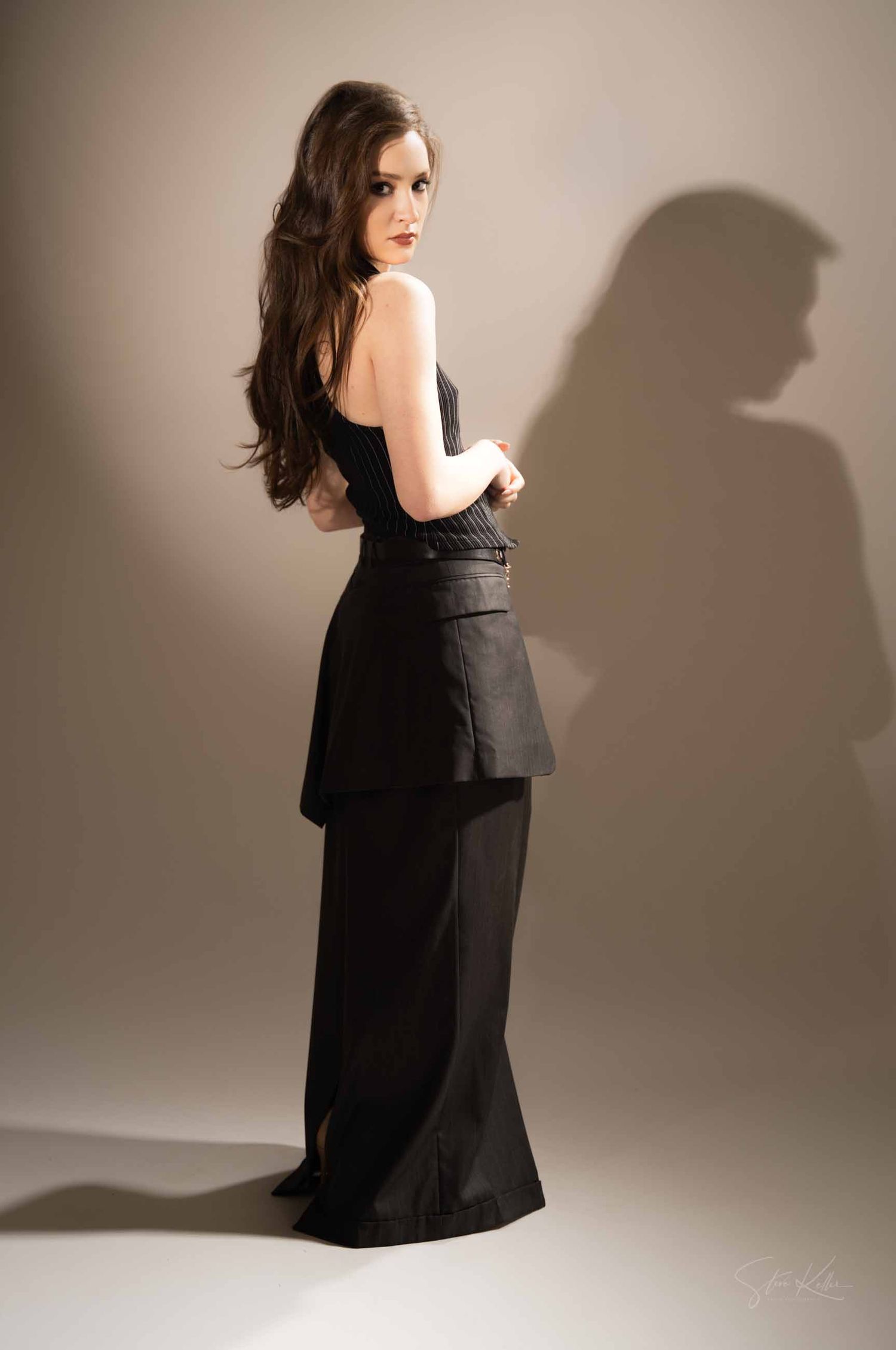 Fashion photoshoot sequence featuring model in black dress posing dynamically against beige studio backdrop.