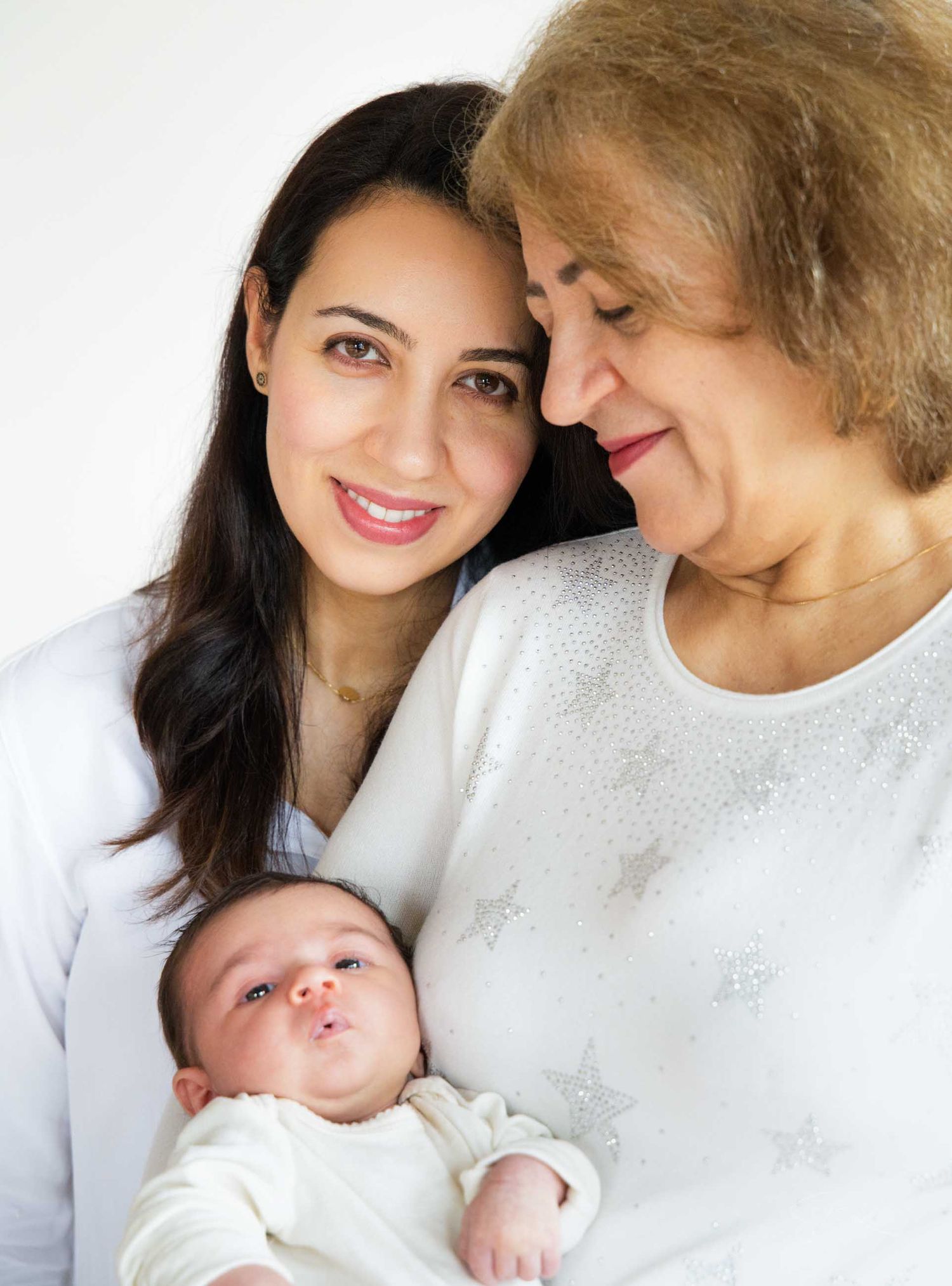A loving family moment captured in a series of intimate portraits with a newborn baby in white attire.