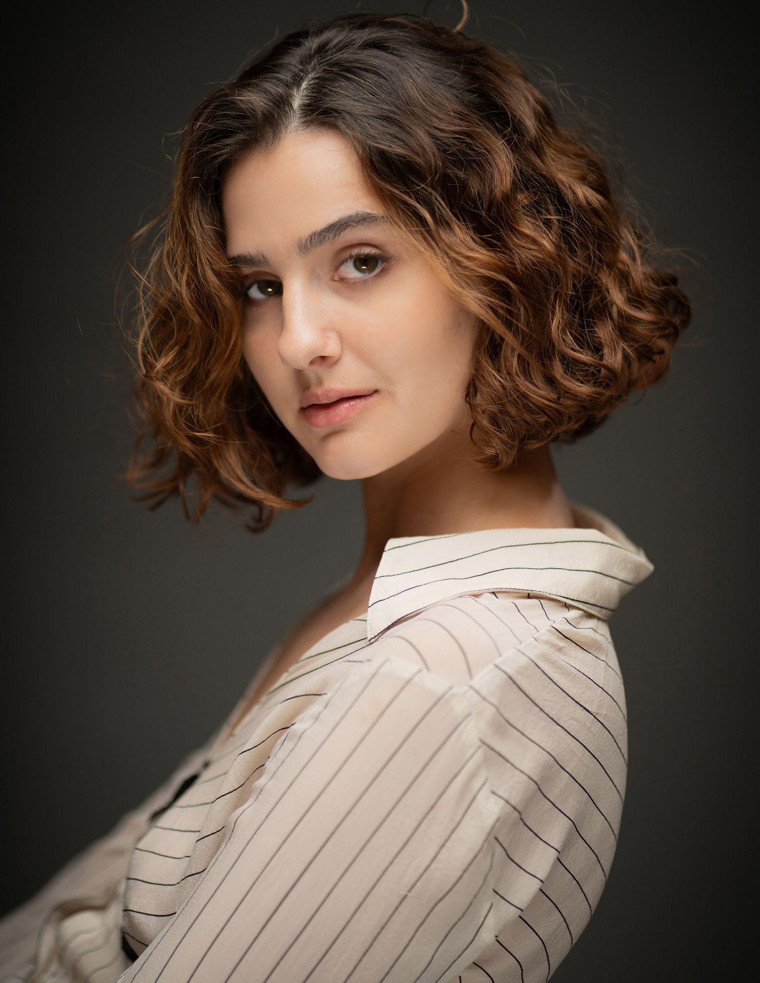 Fashion portrait series with white striped shirt against dark background showcasing elegant styling and curled hair.