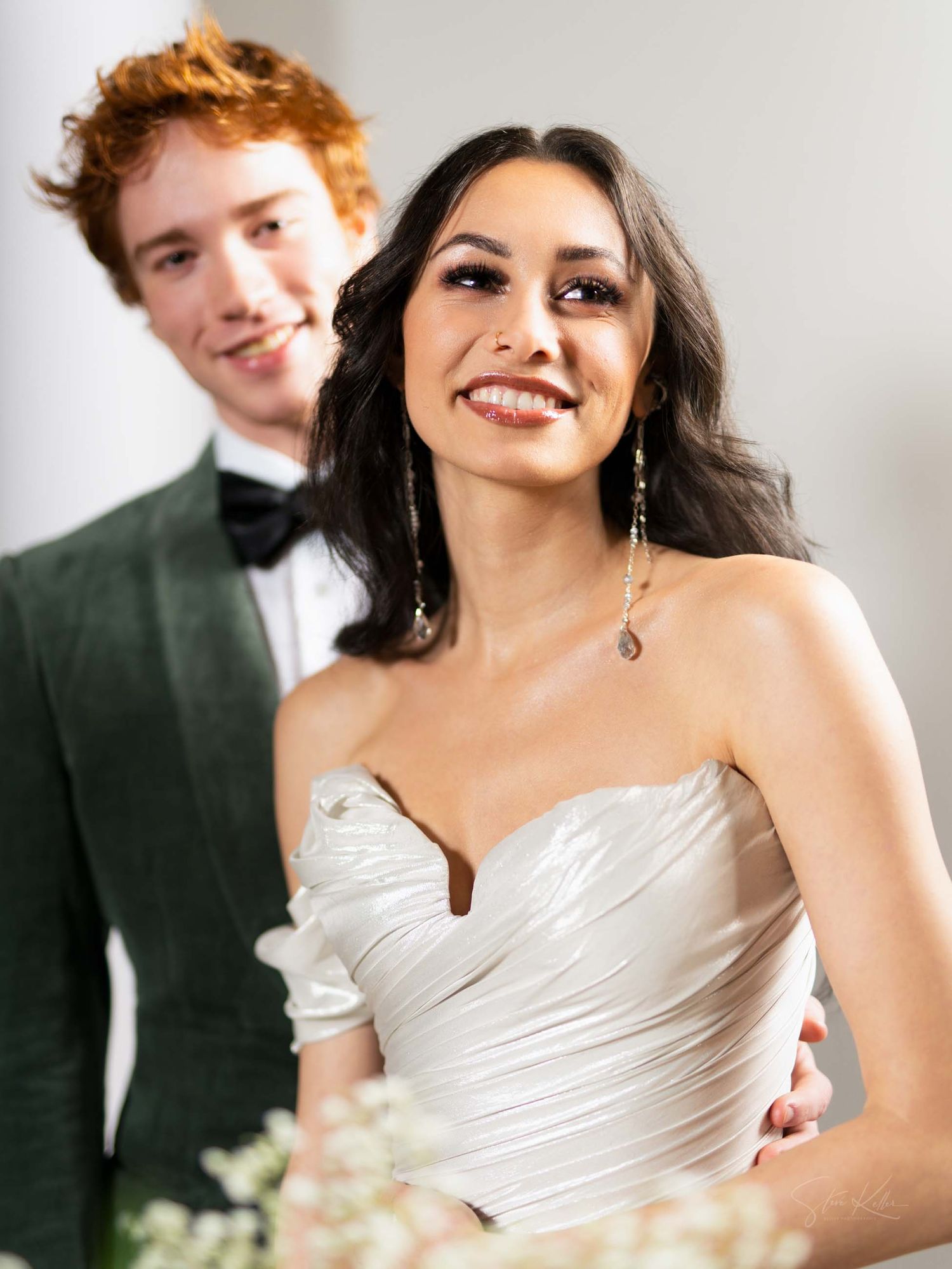 A happy couple in formal wedding attire share candid moments together in a bright studio setting.