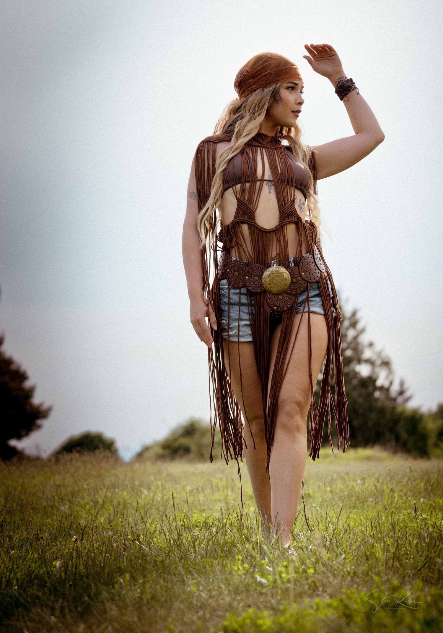 A bohemian style photo shoot in a meadow featuring fringe leather clothing and Native American inspired accessories.