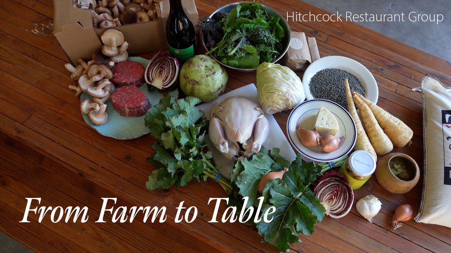 Fresh farm-to-table ingredients including vegetables, herbs, and proteins displayed on a wooden table by Hitchcock Restaurant Group.