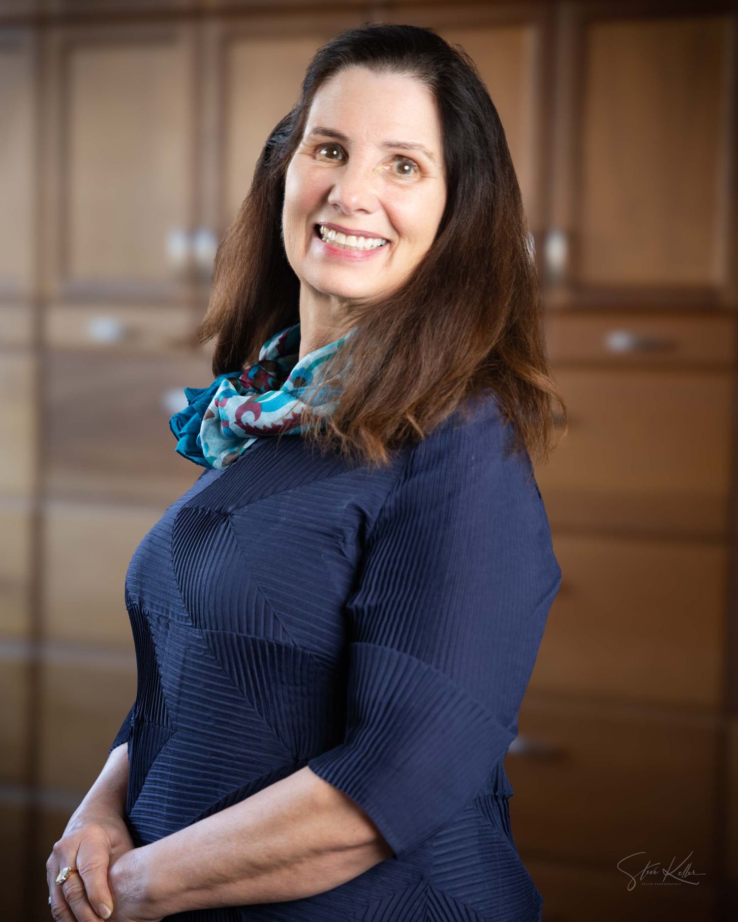 Woman in navy blue sweater poses against wooden background with warm lighting and natural expressions.