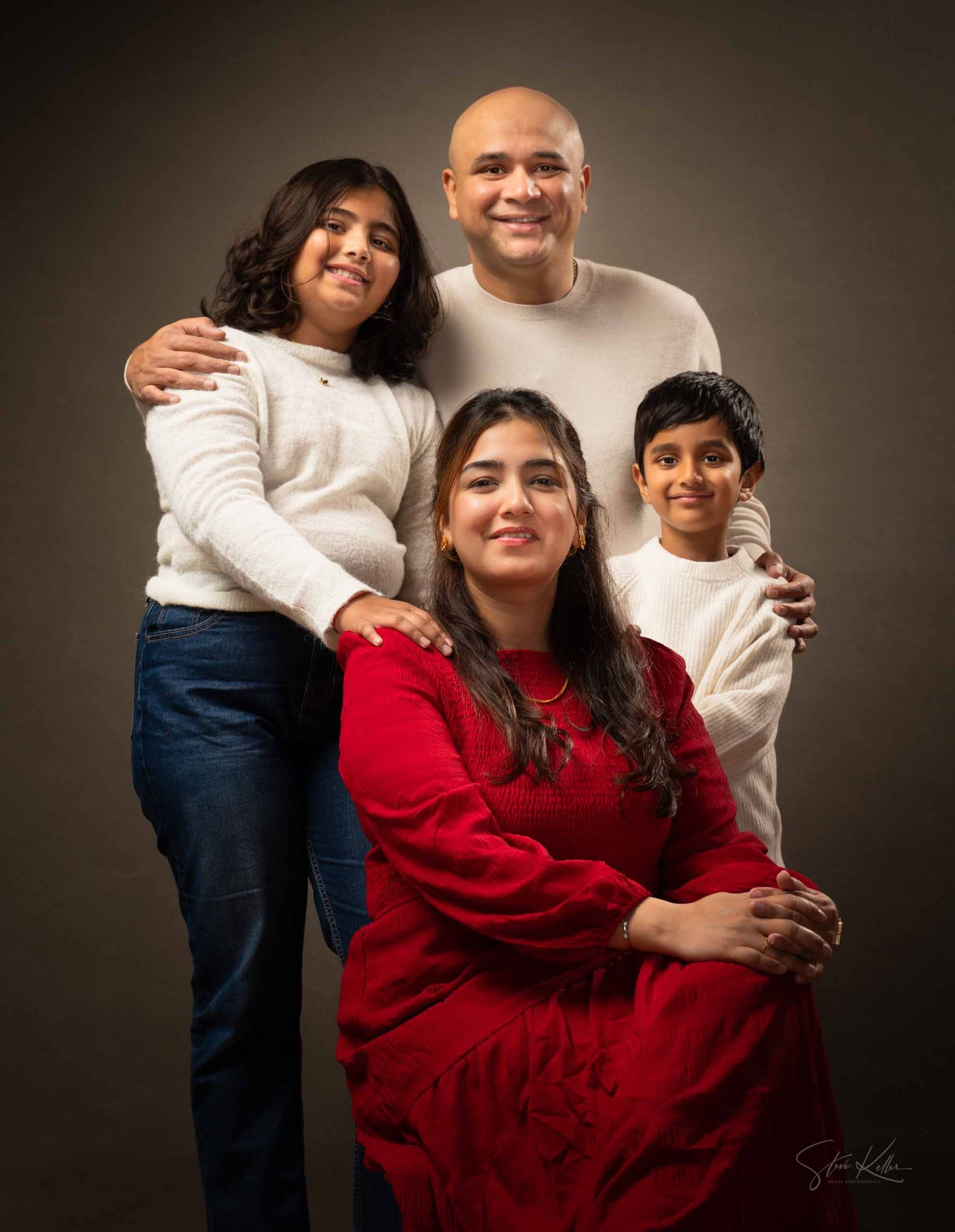 A couple in casual attire poses against a dark background in a series of warm, intimate portrait photographs.