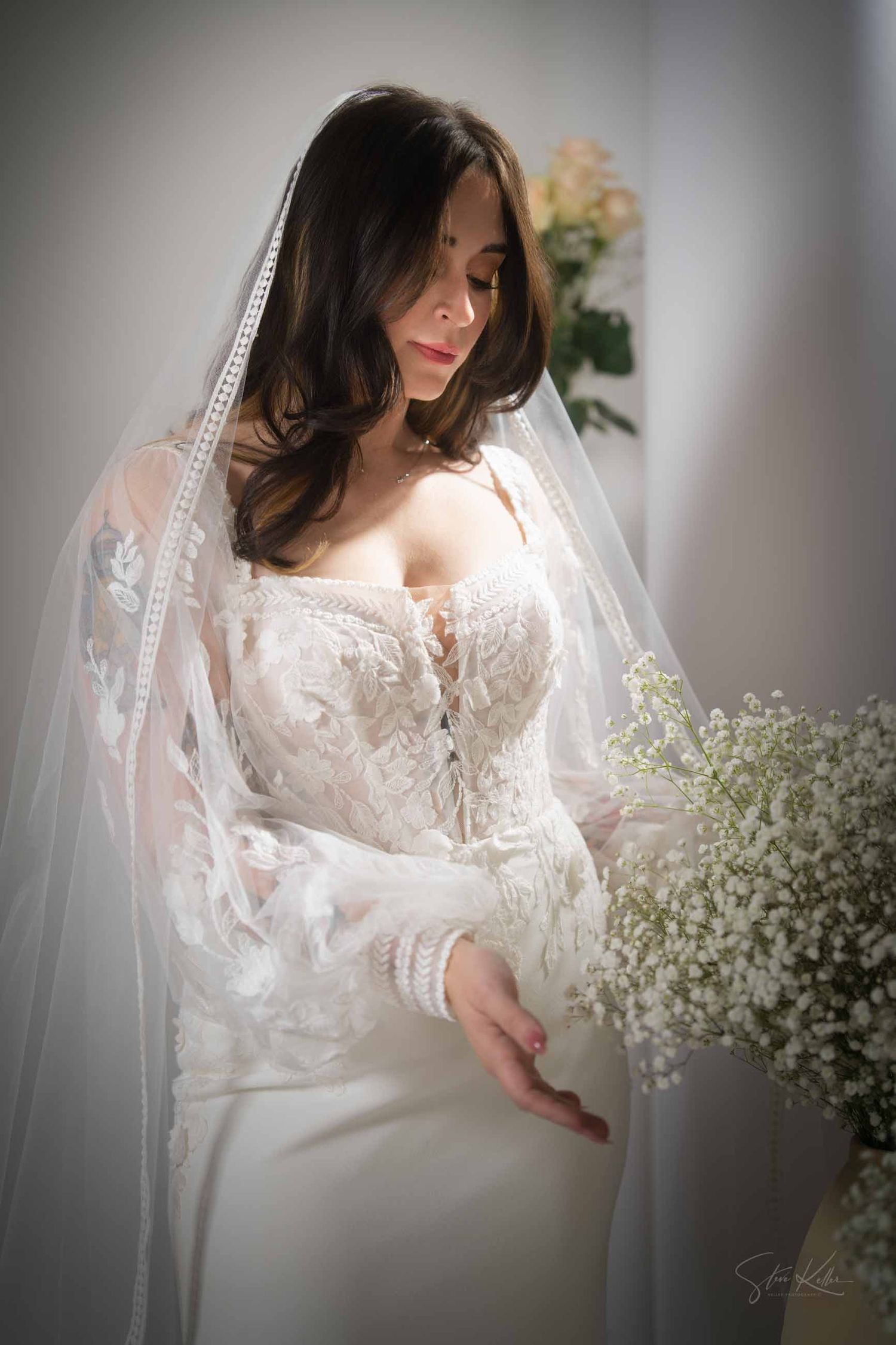 Ethereal bridal portrait featuring delicate lace details, a flowing veil, and romantic baby's breath flowers in soft lighting.