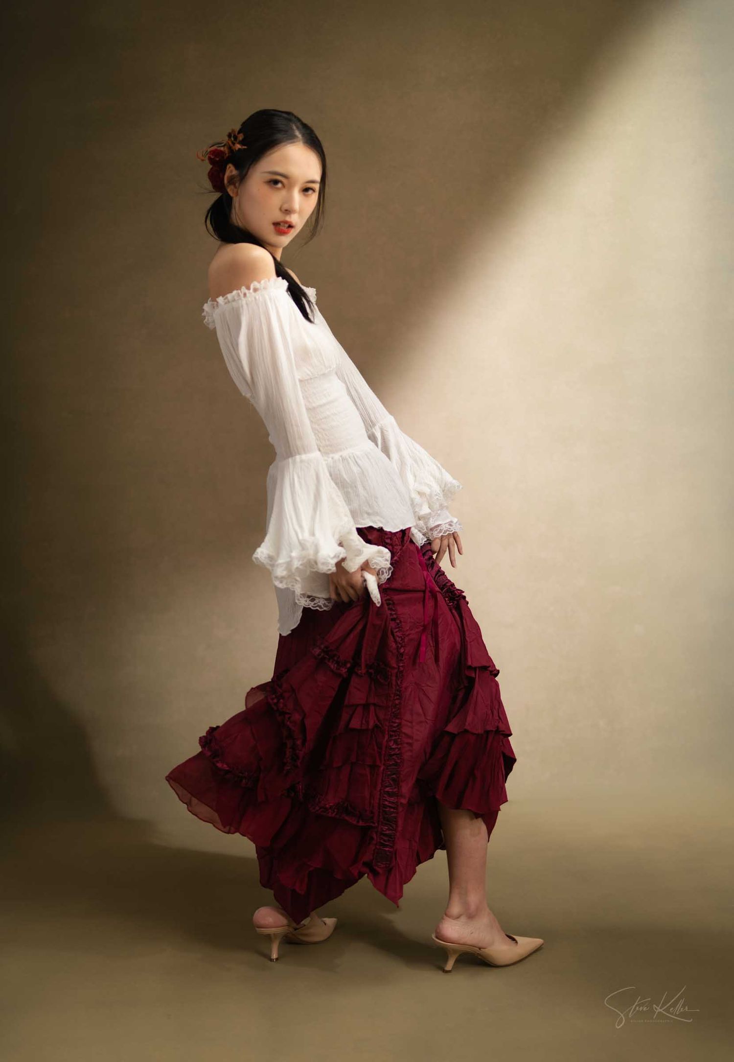 A figure in a flowing white blouse and burgundy ruffled skirt poses gracefully in a series of artistic studio portraits.