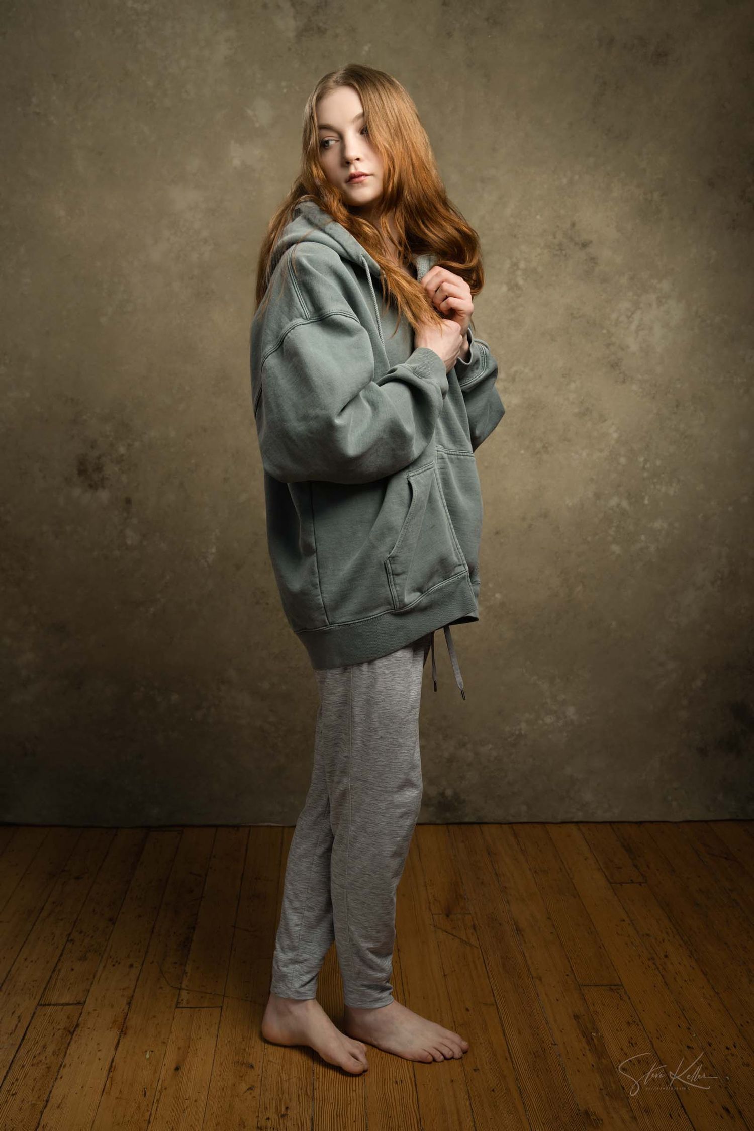 Multiple views of someone wearing a grey and sage green outfit on a wooden floor with textured wall.
