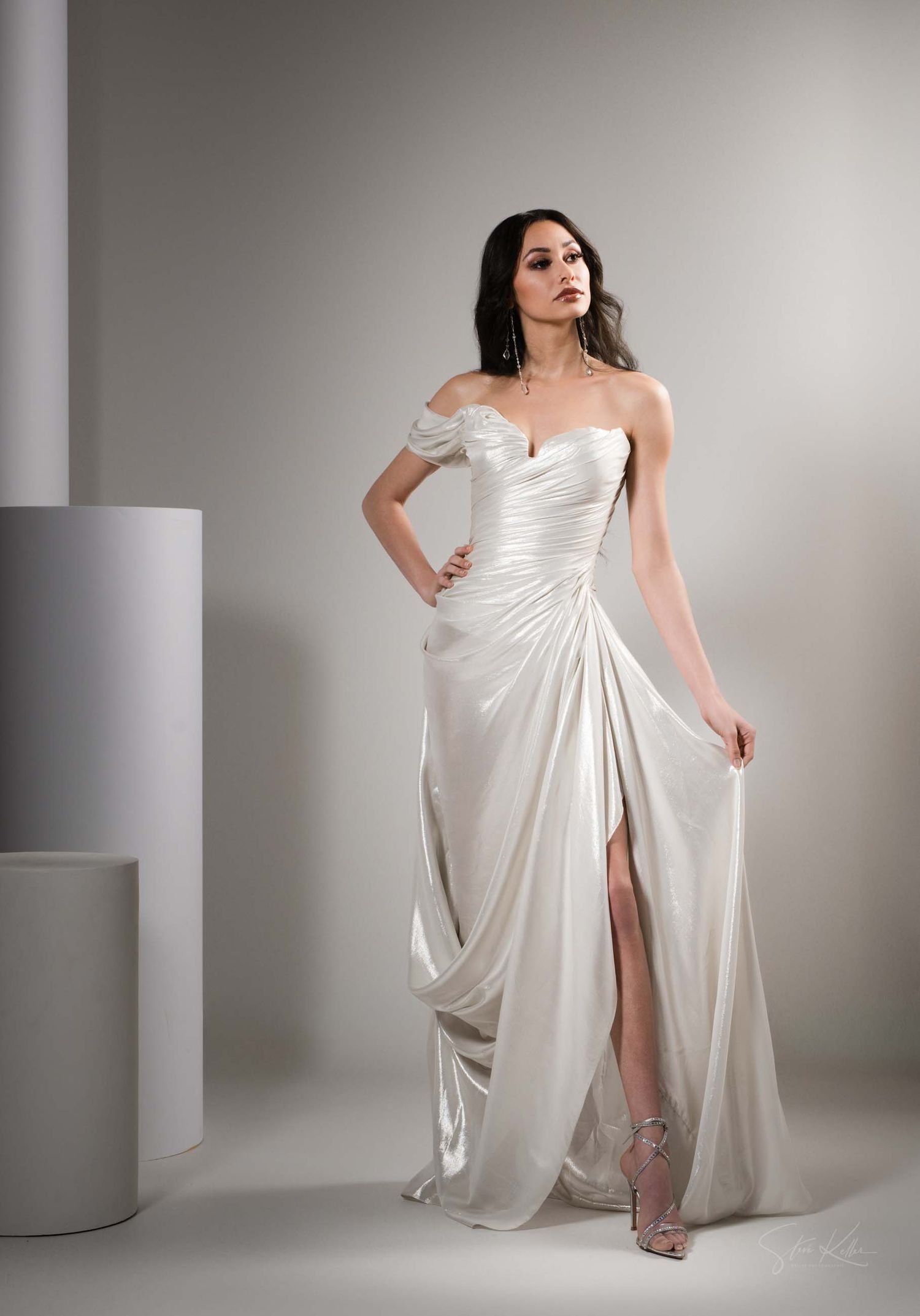 A flowing white evening gown with draped fabric and side slit photographed in sequence against a neutral studio backdrop.