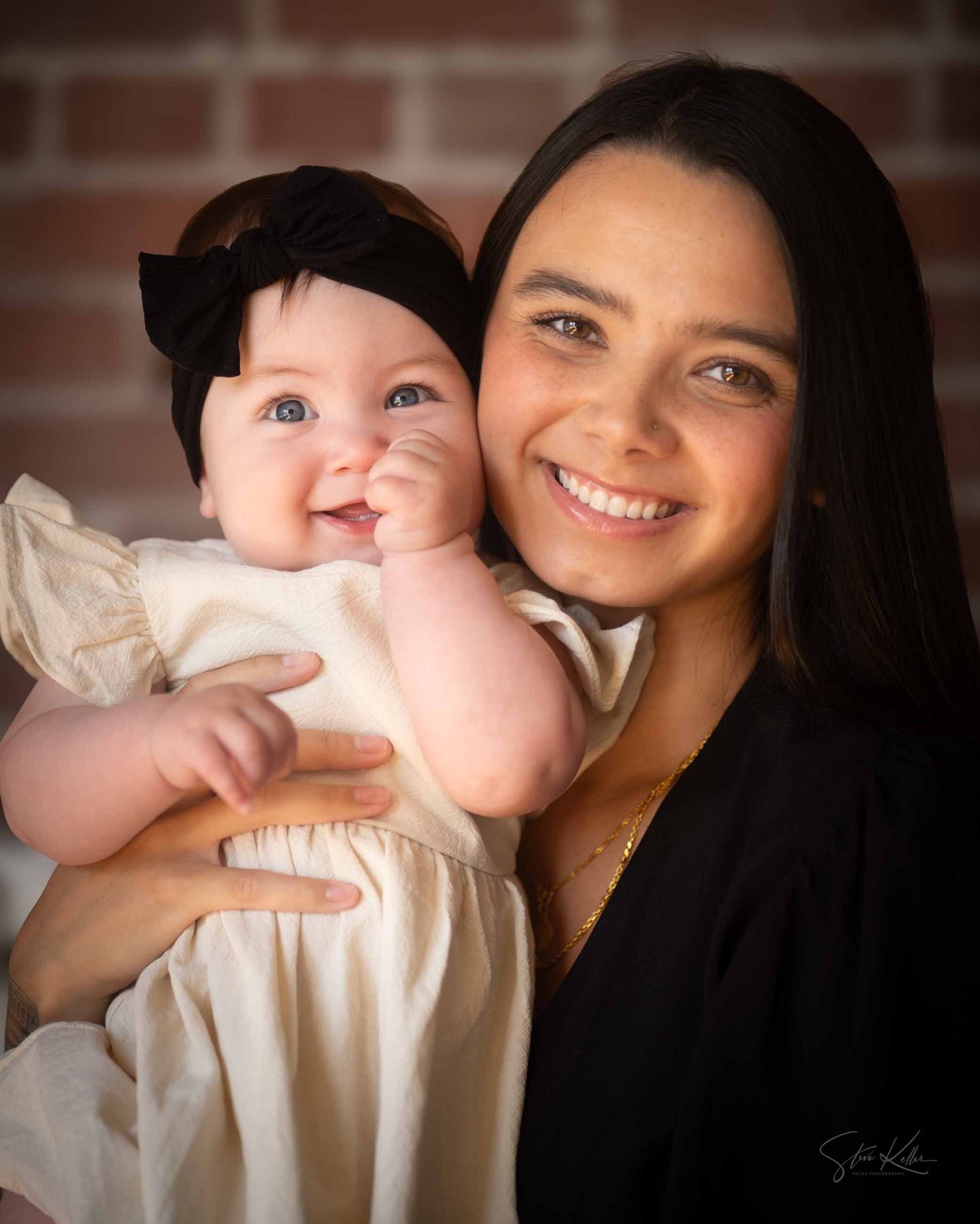 A series of four intimate portrait photographs showing tender moments between parent and baby against a brick background.