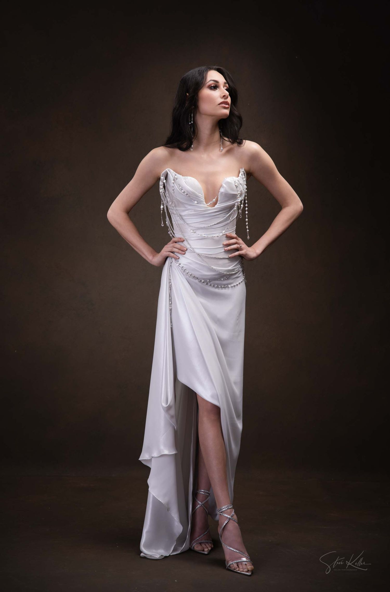 Dramatic fashion portraits with white draped dress against dark background showing elegant poses.