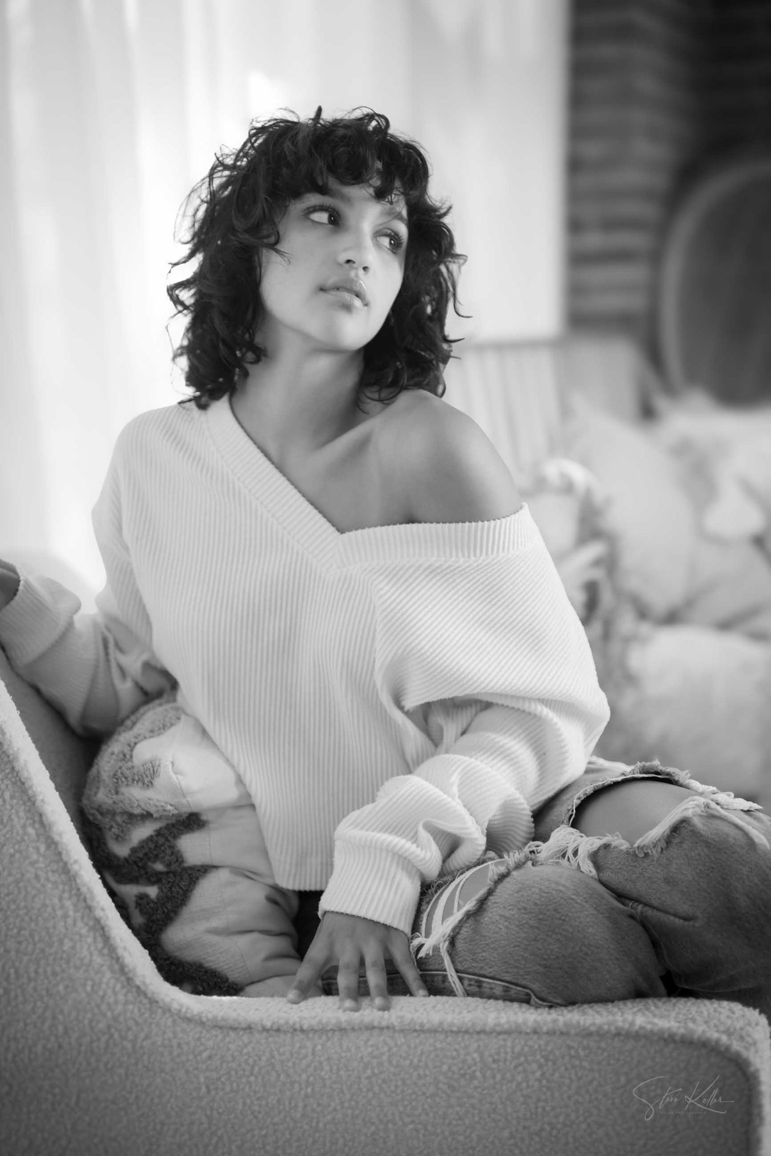 Black and white boudoir photo series showing a model in a white sweater reclining on a couch.