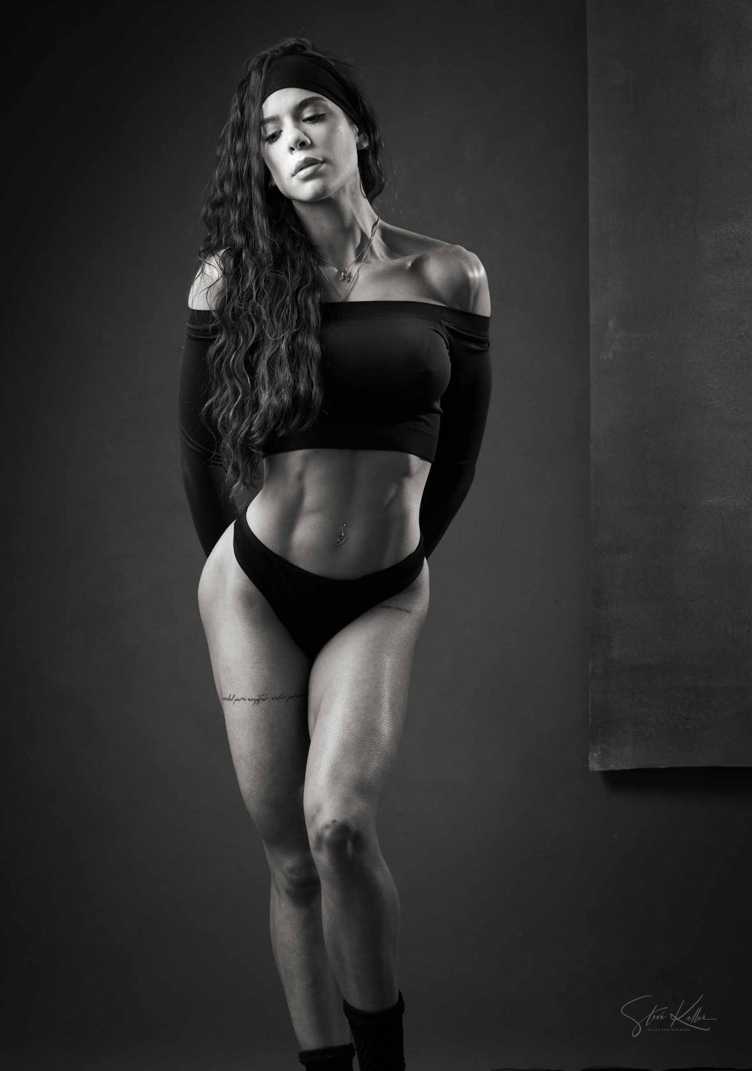 Artistic black and white portrait of a figure in dark clothing against a shadowy background.