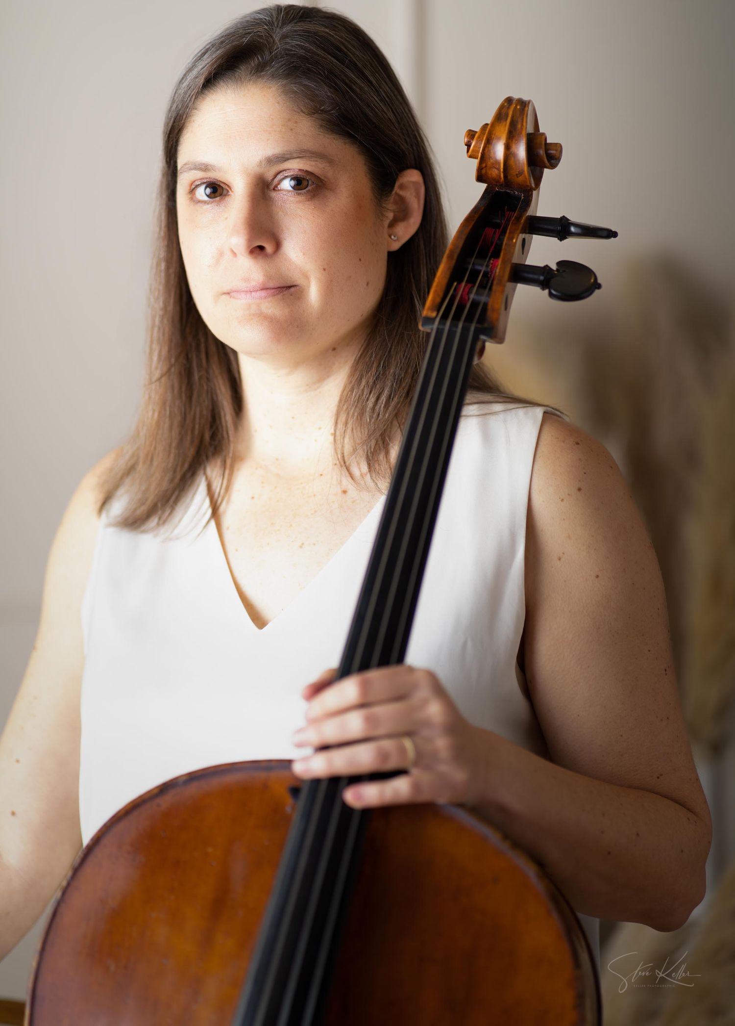A musician in a white sleeveless top holds and plays a wooden cello in a series of progressive shots.