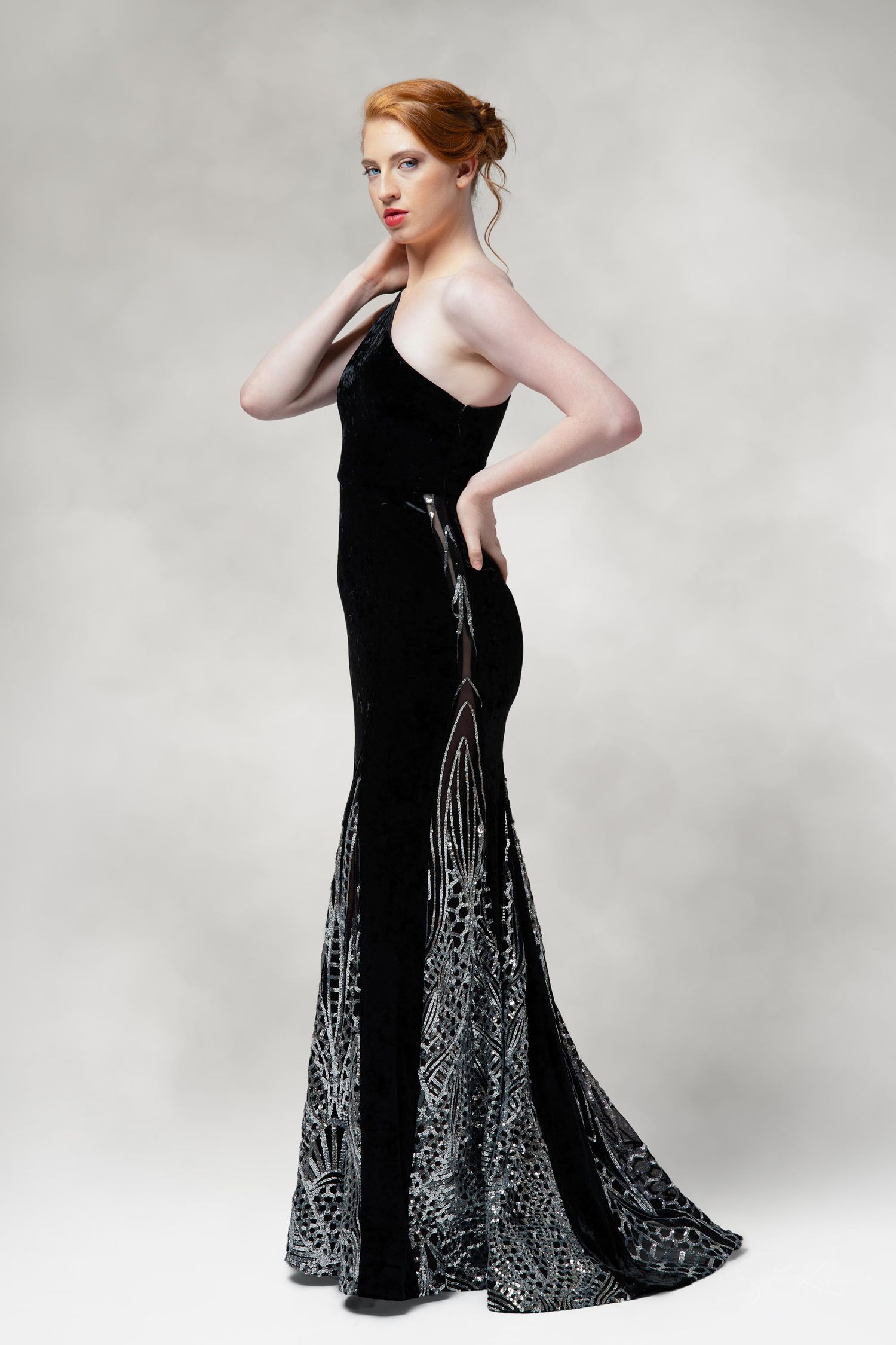 Woman in a black evening gown with silver metallic details strikes elegant poses against a light gray studio backdrop.