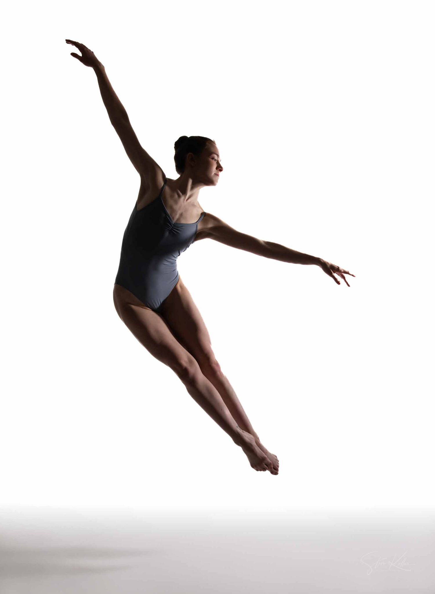 A dancer in a grey leotard performs a graceful leap sequence against a white background, showing dynamic movement.