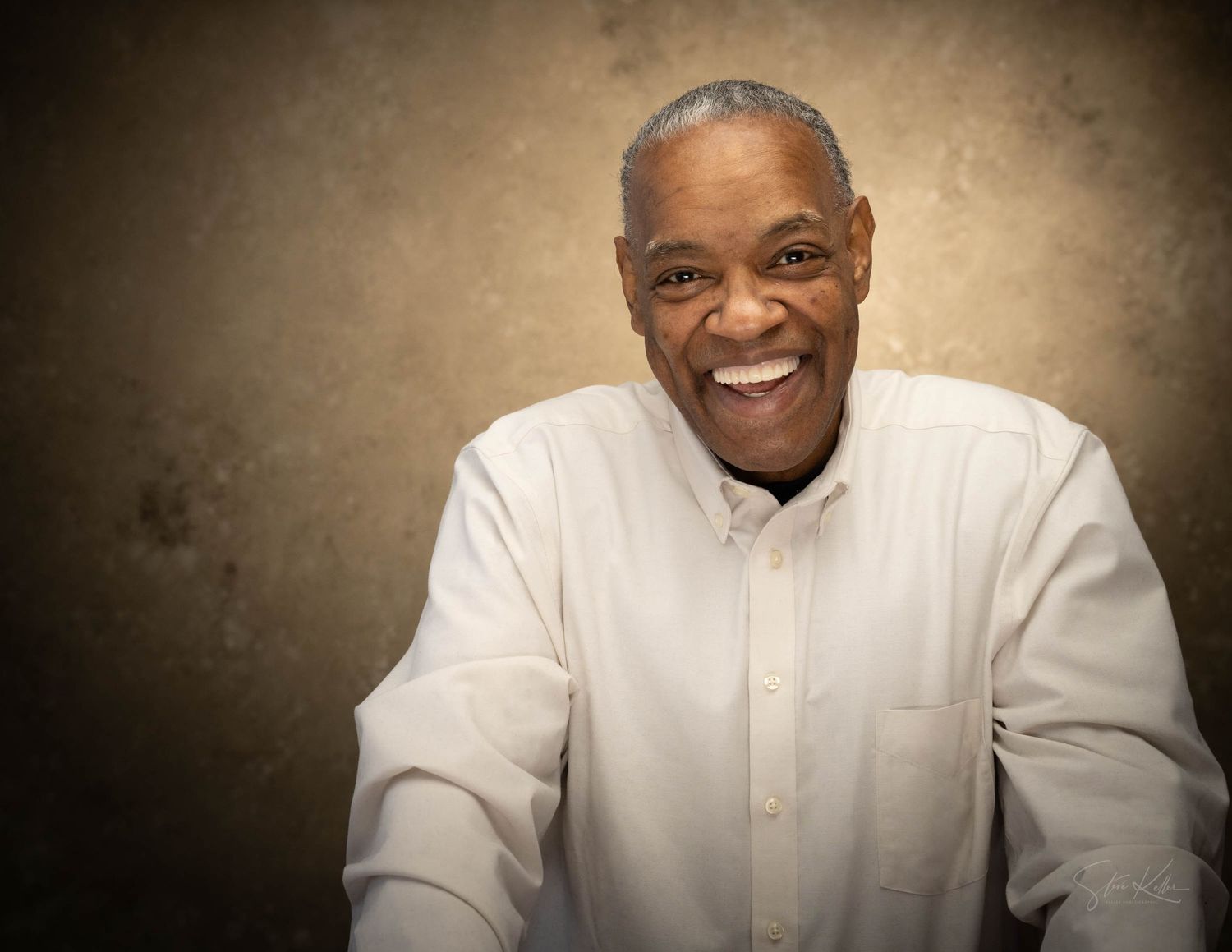 Warm portrait of a person in a white button-down shirt with an enthusiastic expression.