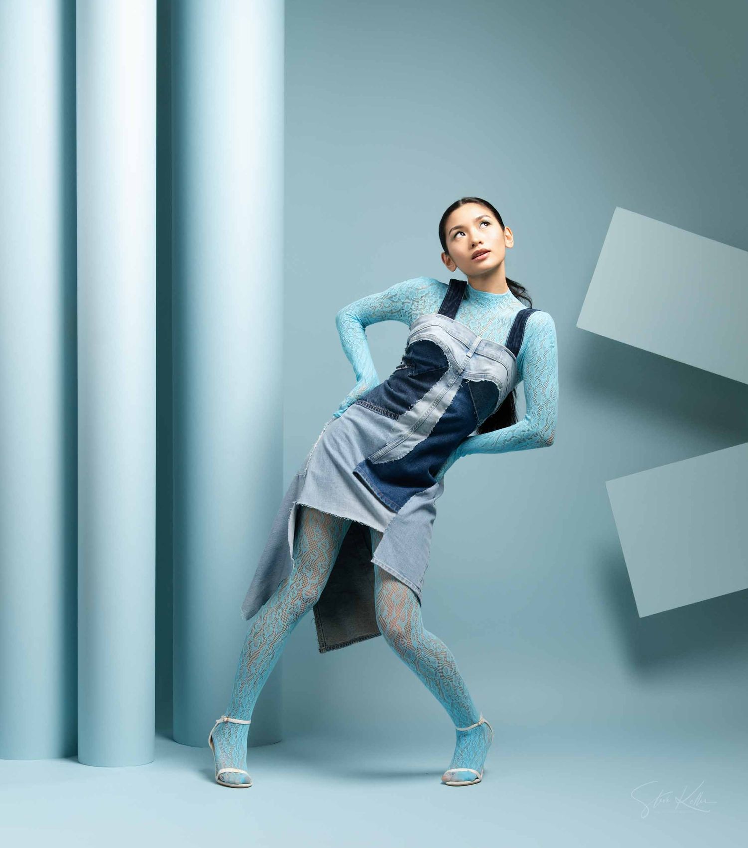 Athletic figure in blue and gray activewear strikes dynamic pose against geometric background in studio setting.