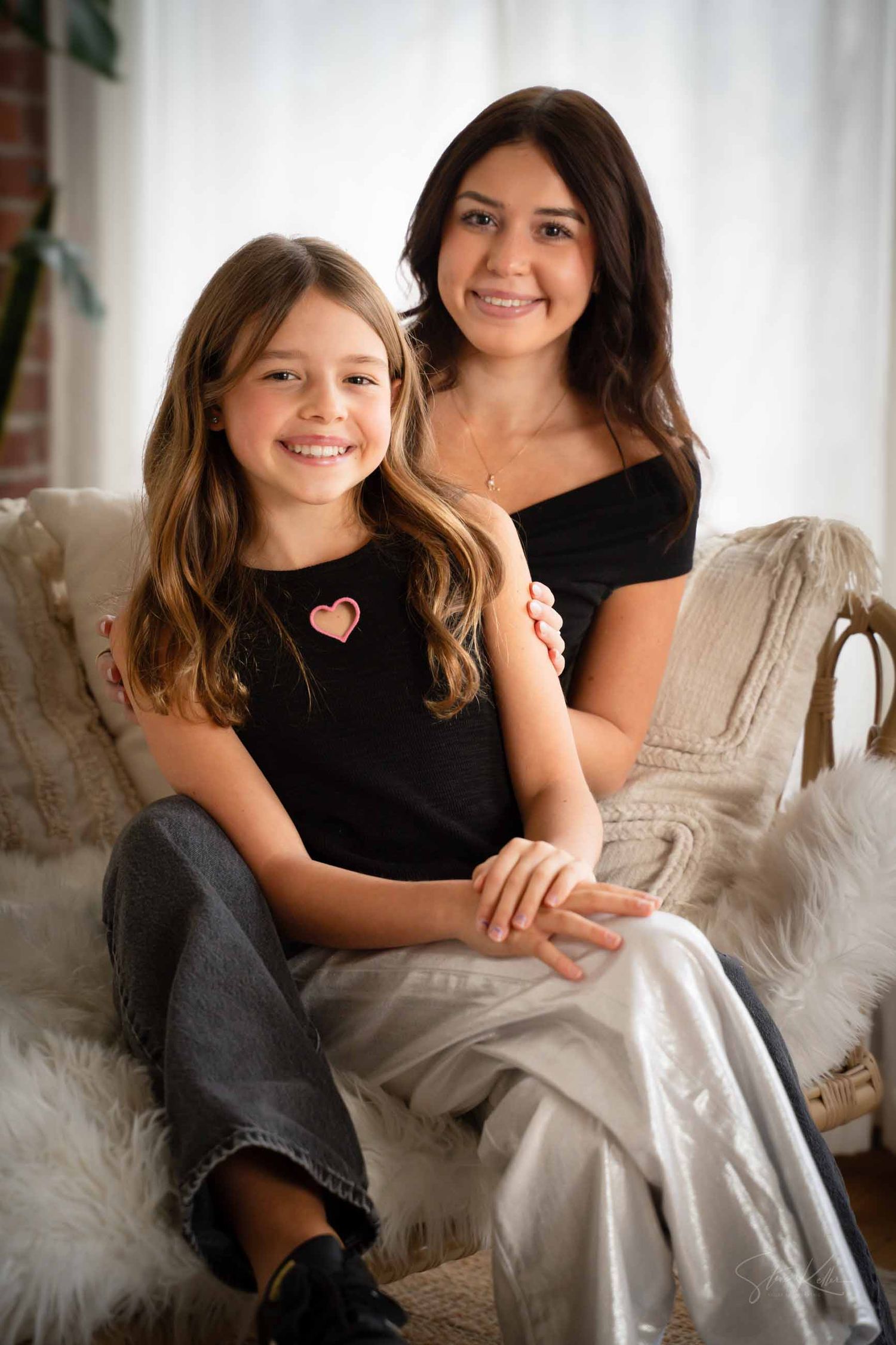 Two people sit together on a couch sharing warm smiles and laughter in a bright indoor setting.