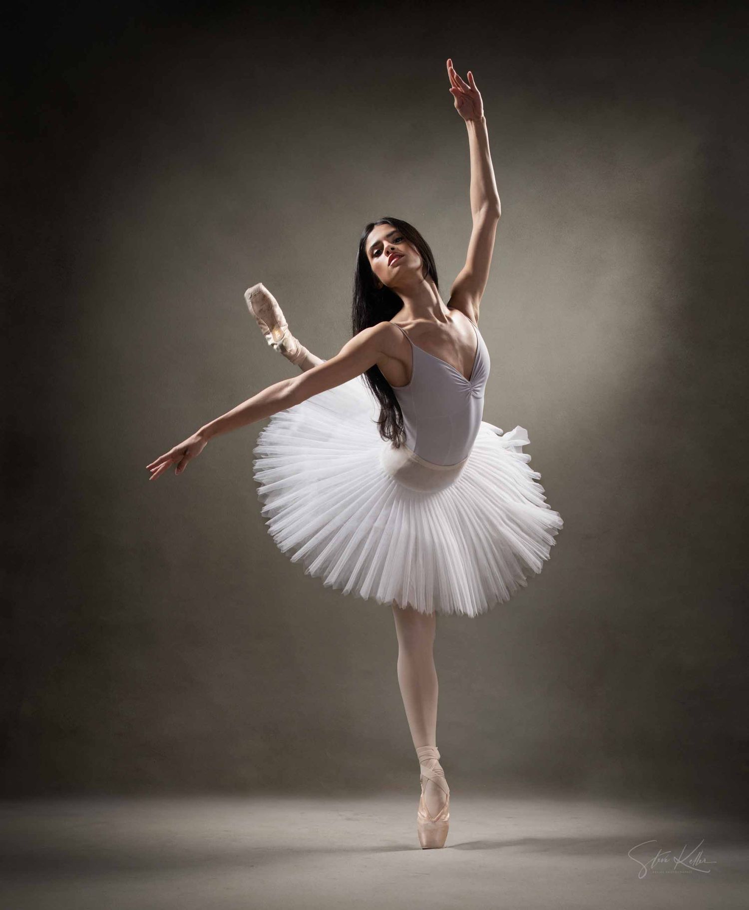 A ballet dancer in a white tutu performs graceful poses against a dark background in a series of elegant shots.