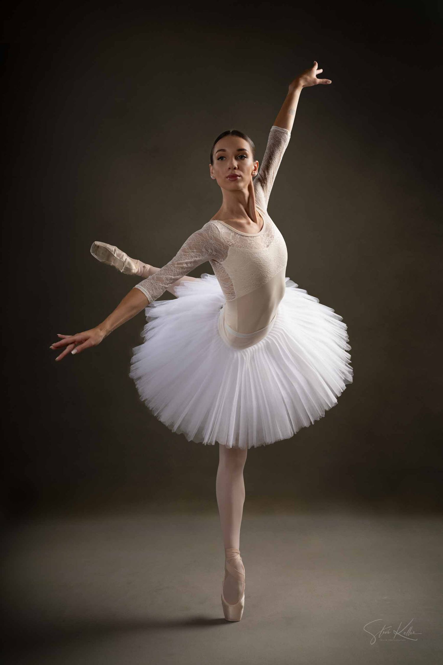 A ballet dancer in a white tutu performs graceful poses in a dramatic studio lighting sequence.