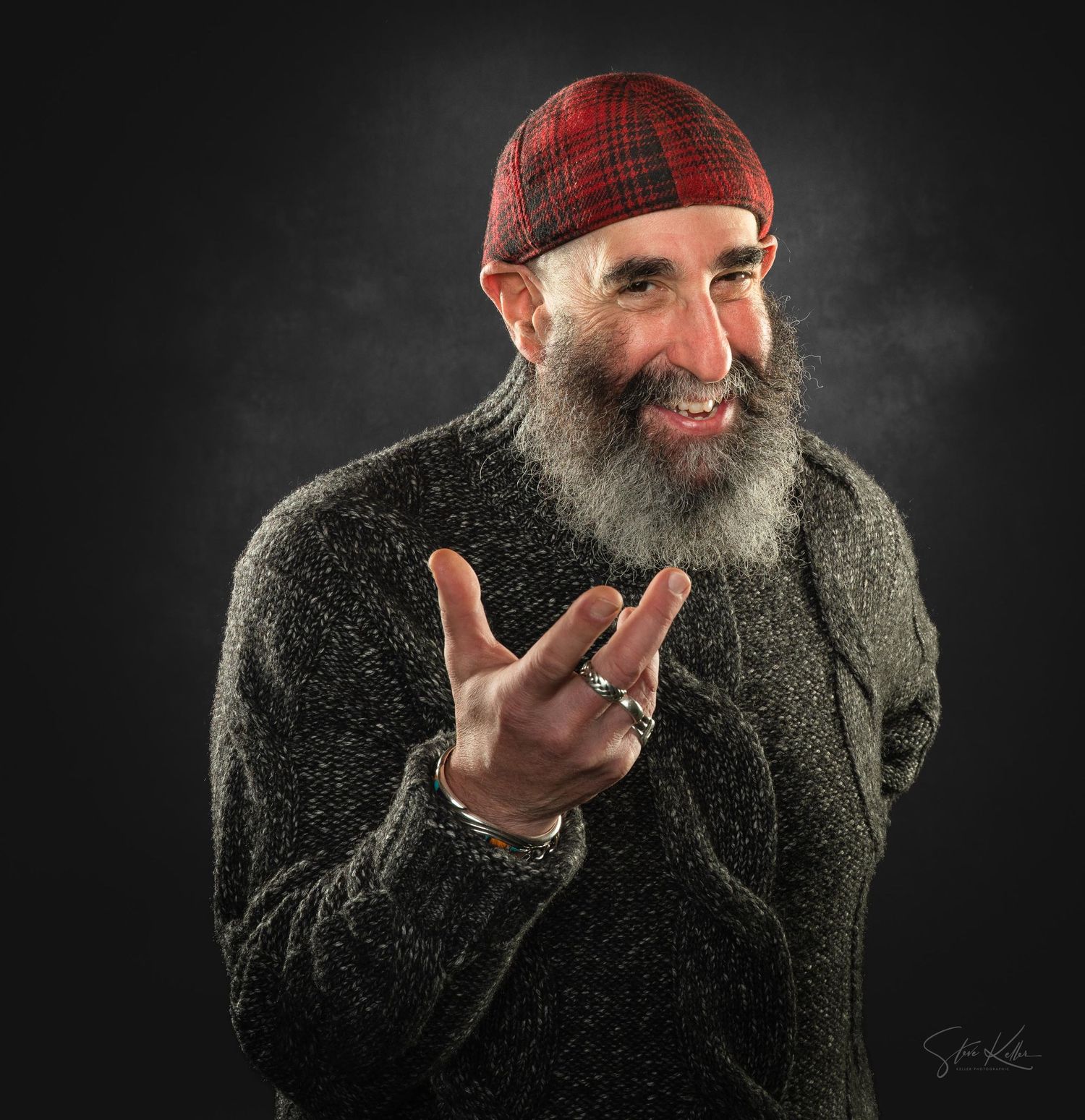 A bearded man in a dark winter coat gestures playfully against a black background in a split-frame sequence.
