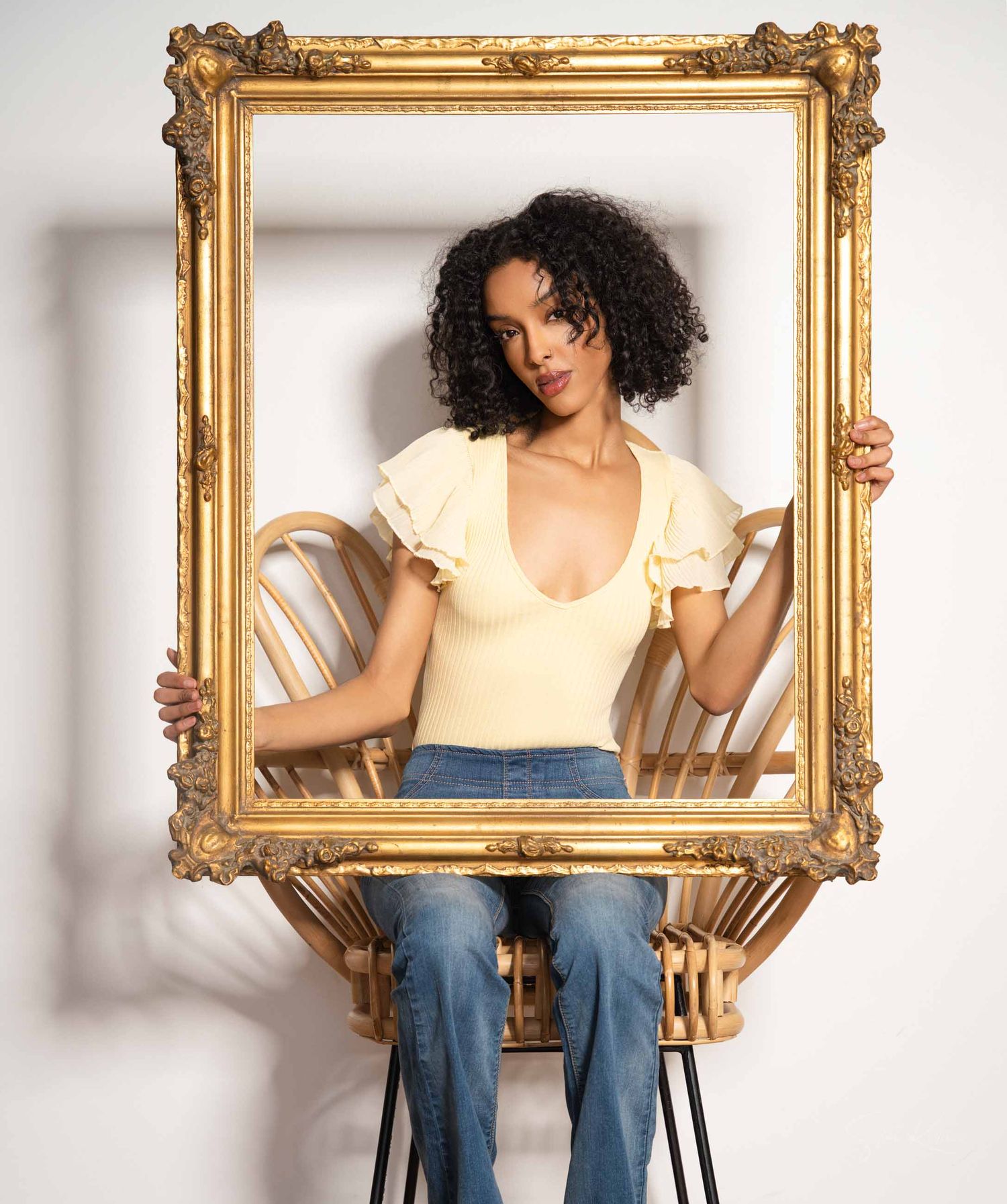 A series of four photos showing a person in jeans and yellow top posing with an ornate gold picture frame.