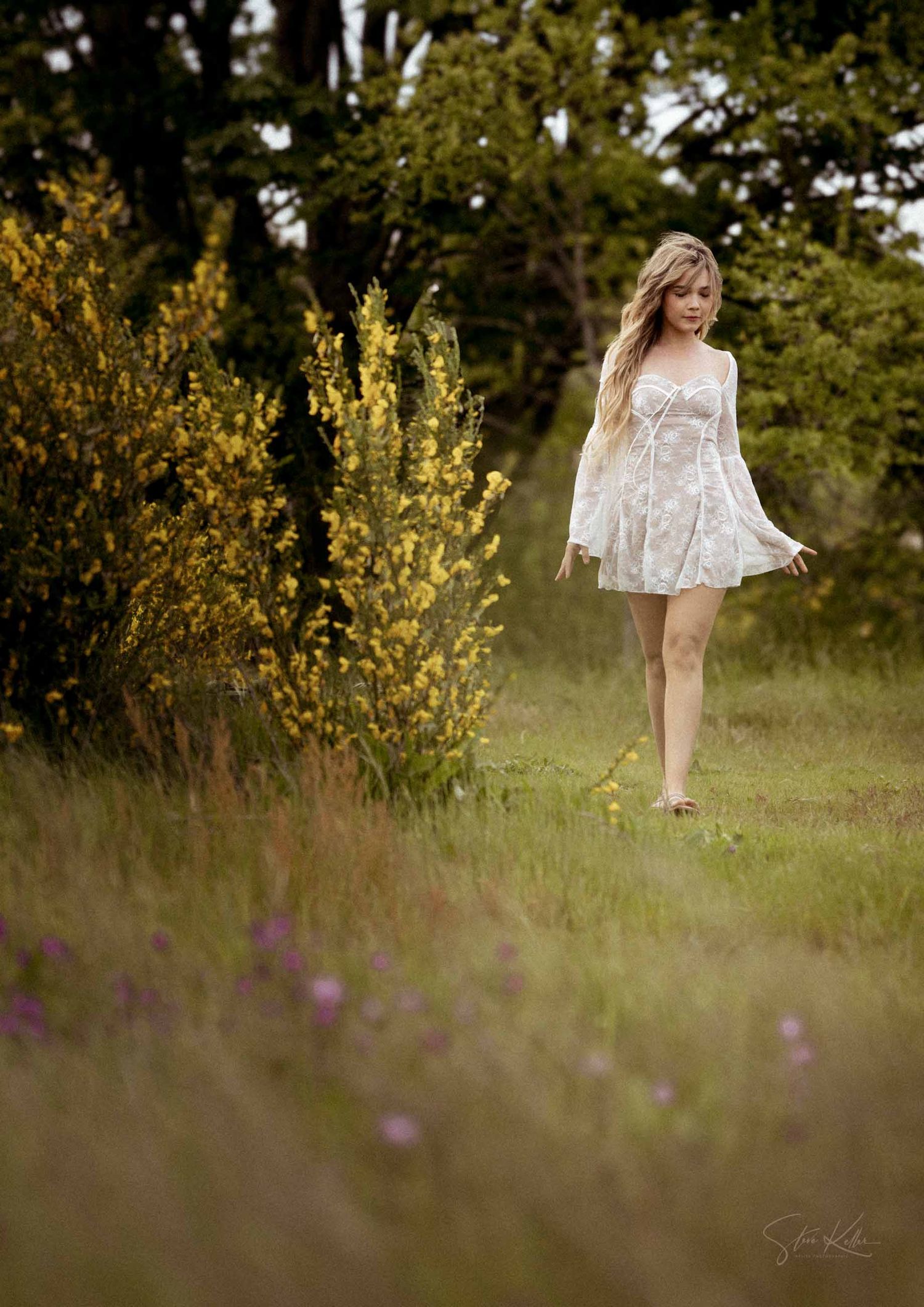 A dreamy outdoor portrait session in a wildflower meadow at golden hour showcasing a flowing white lace dress.