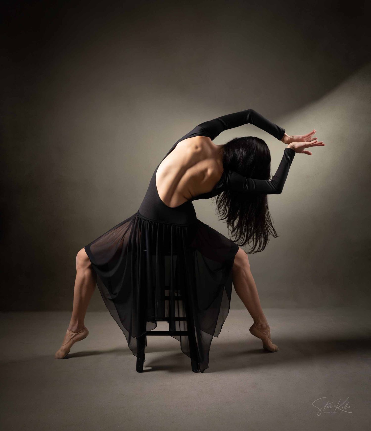 Contemporary dancer in flowing black dress creates dramatic poses in moody studio lighting sequence.