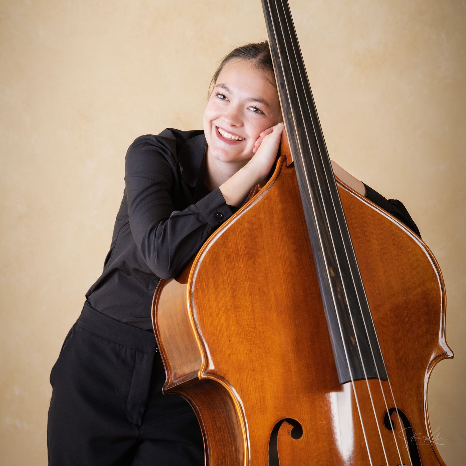 A musician in black attire plays a wooden double bass against a beige backdrop in various expressive poses.