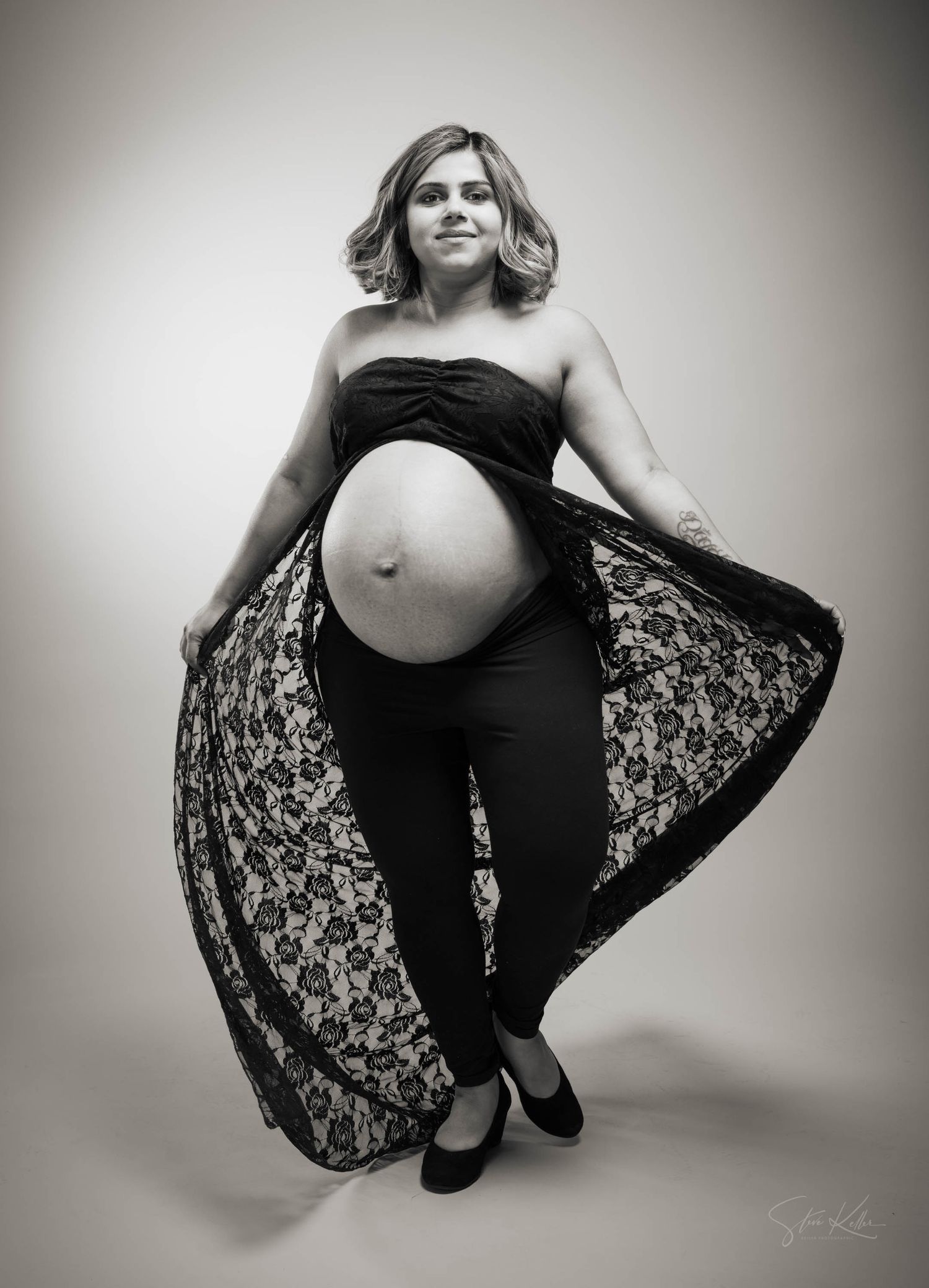 Black and white maternity portraits featuring a woman in flowing dress striking elegant poses against light background.