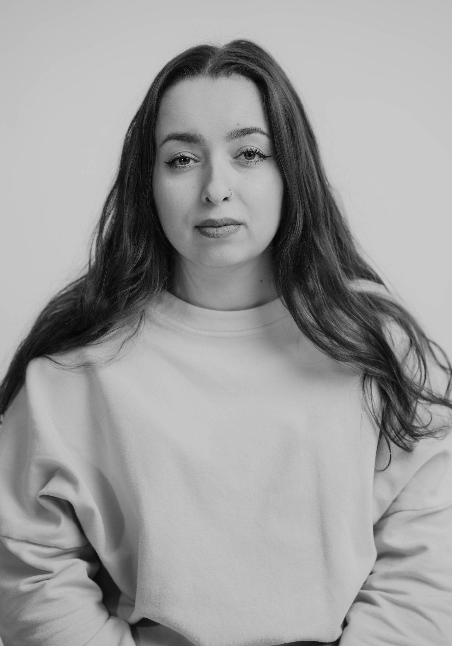 Minimalist black and white portrait in oversized sweatshirt with flowing dark hair.