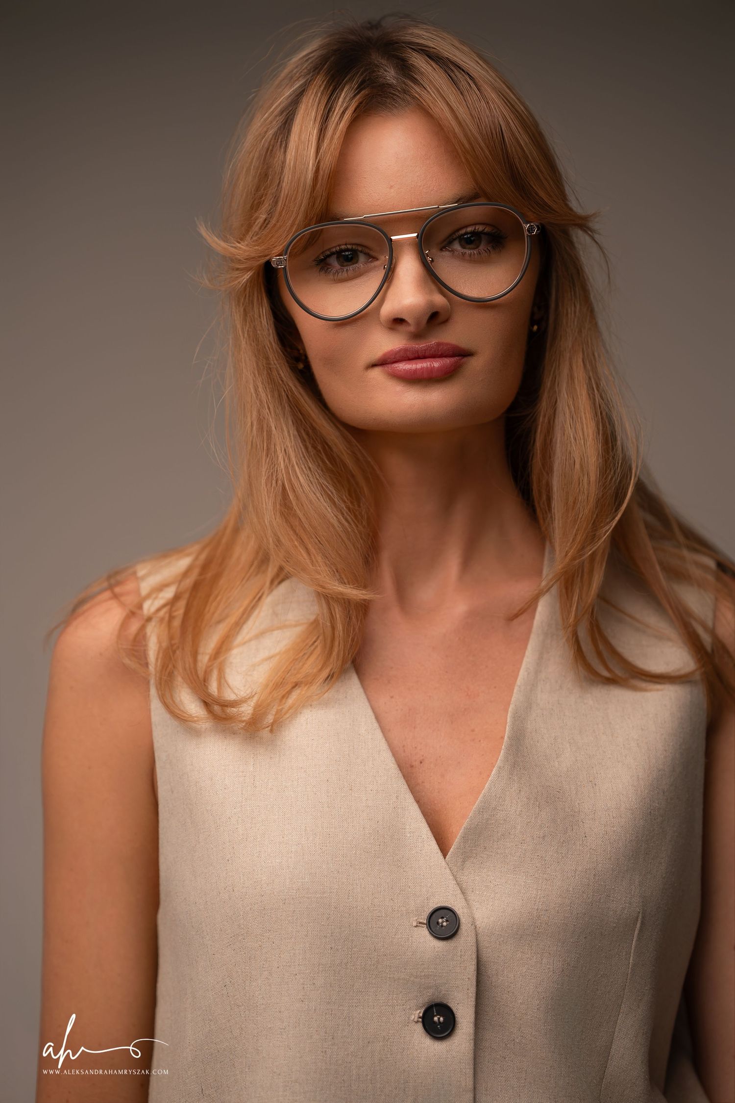 Professional beauty portrait series showing artistic lighting and styling with a beige sleeveless top and round glasses.